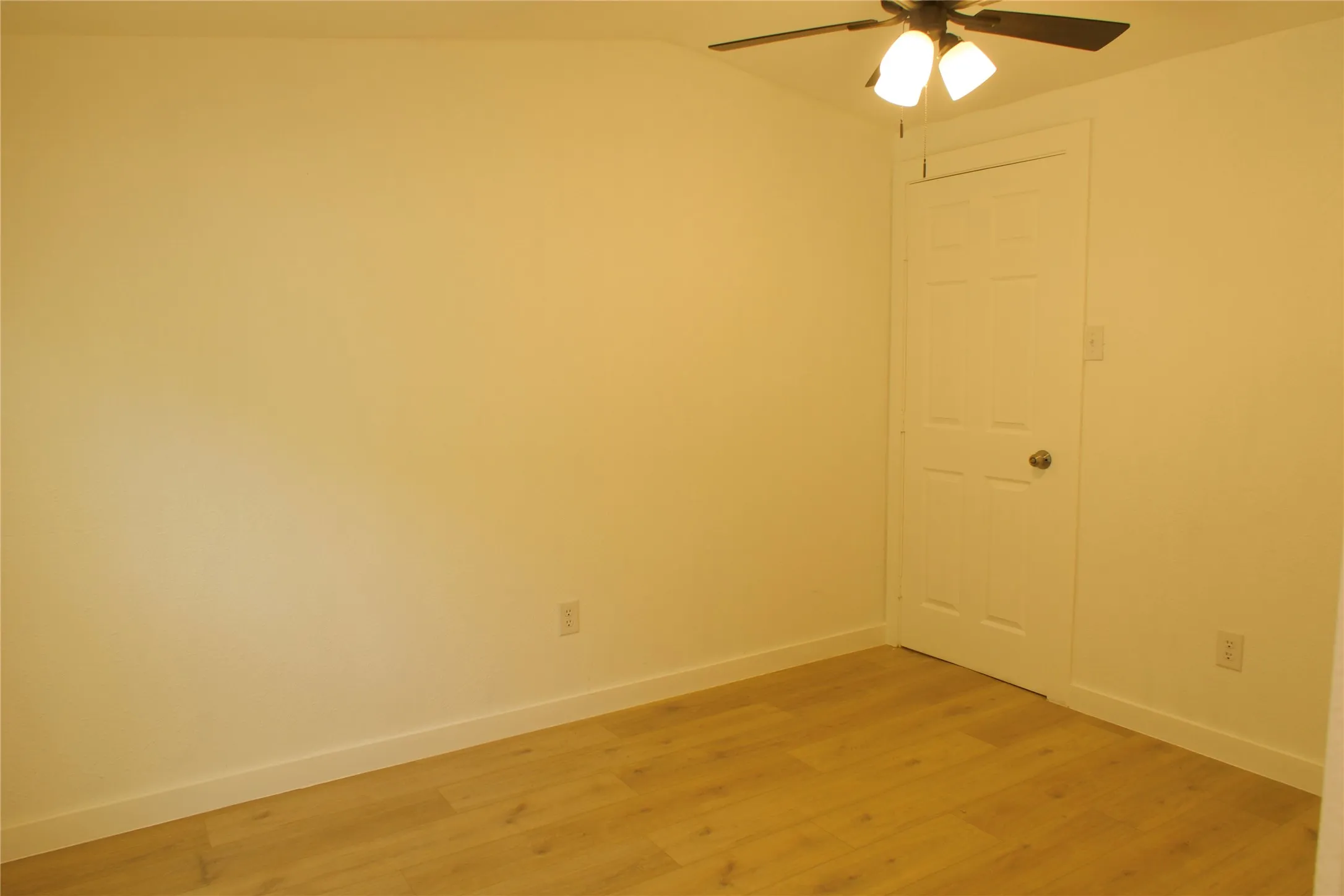 Unfurnished room featuring a ceiling fan, light wood-style floors, baseboards, and vaulted ceiling