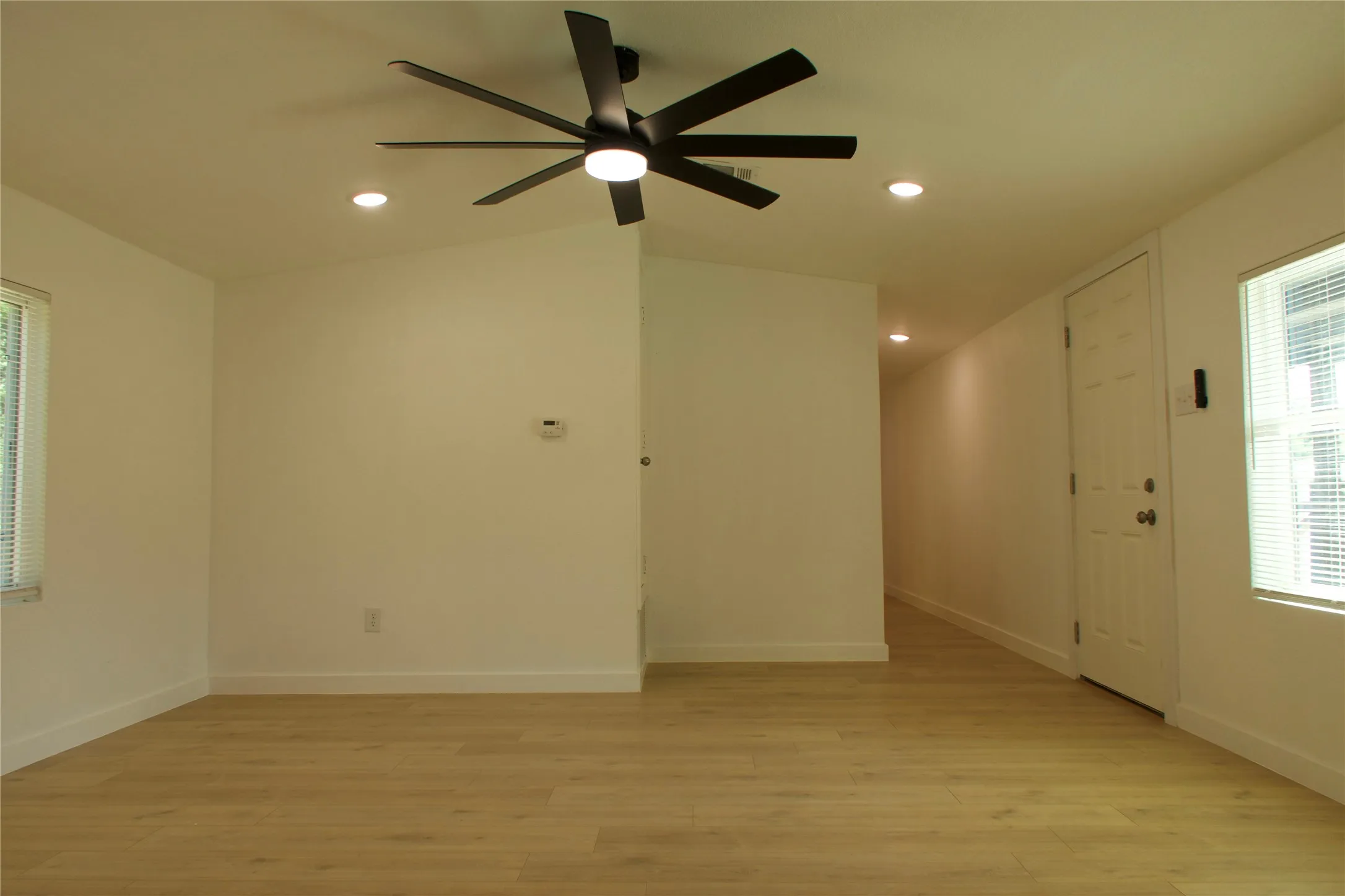 Empty room with light wood-type flooring, a ceiling fan, baseboards, recessed lighting, and lofted ceiling
