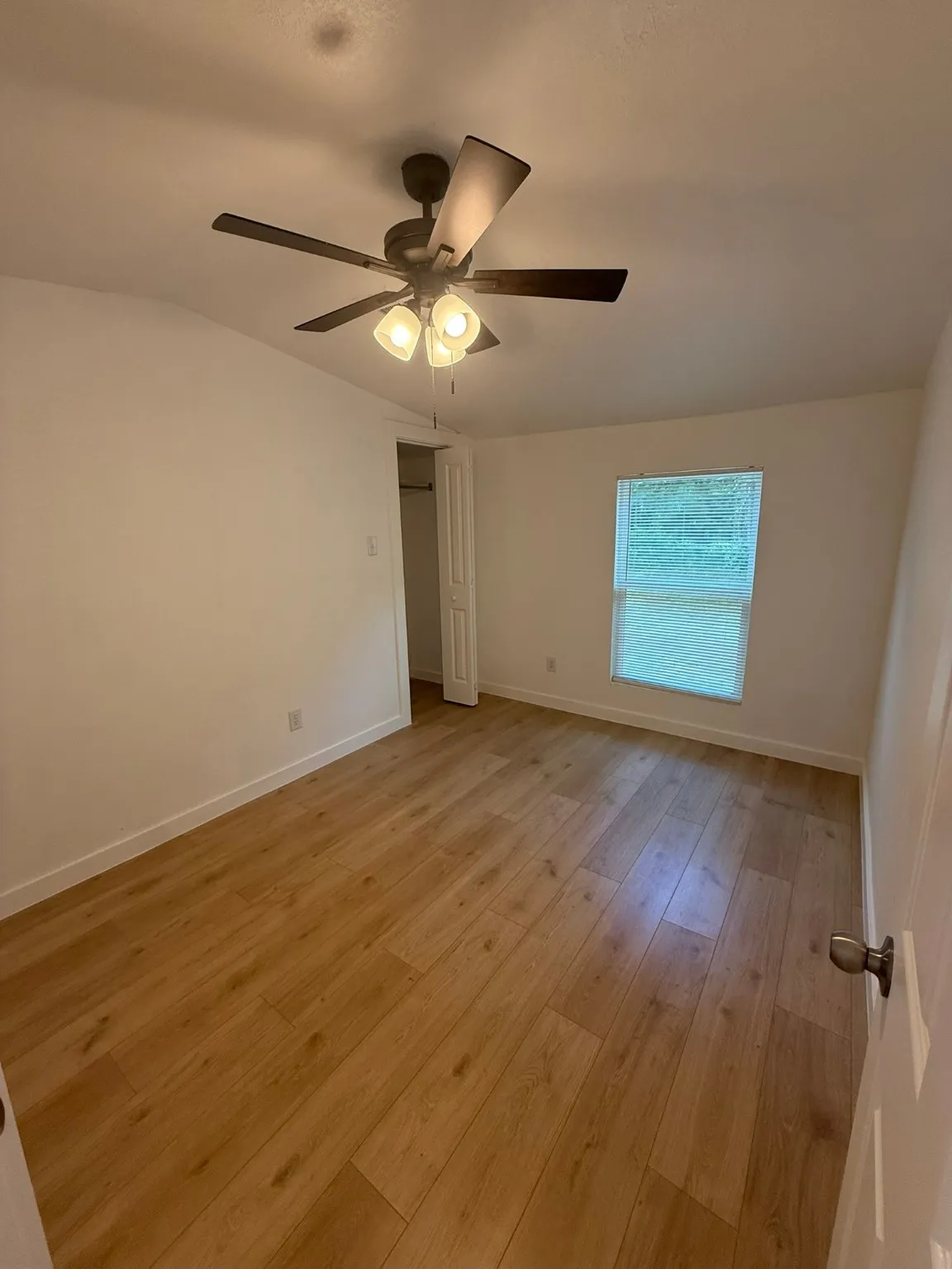 Spare room featuring light wood-style floors, a ceiling fan, and baseboards