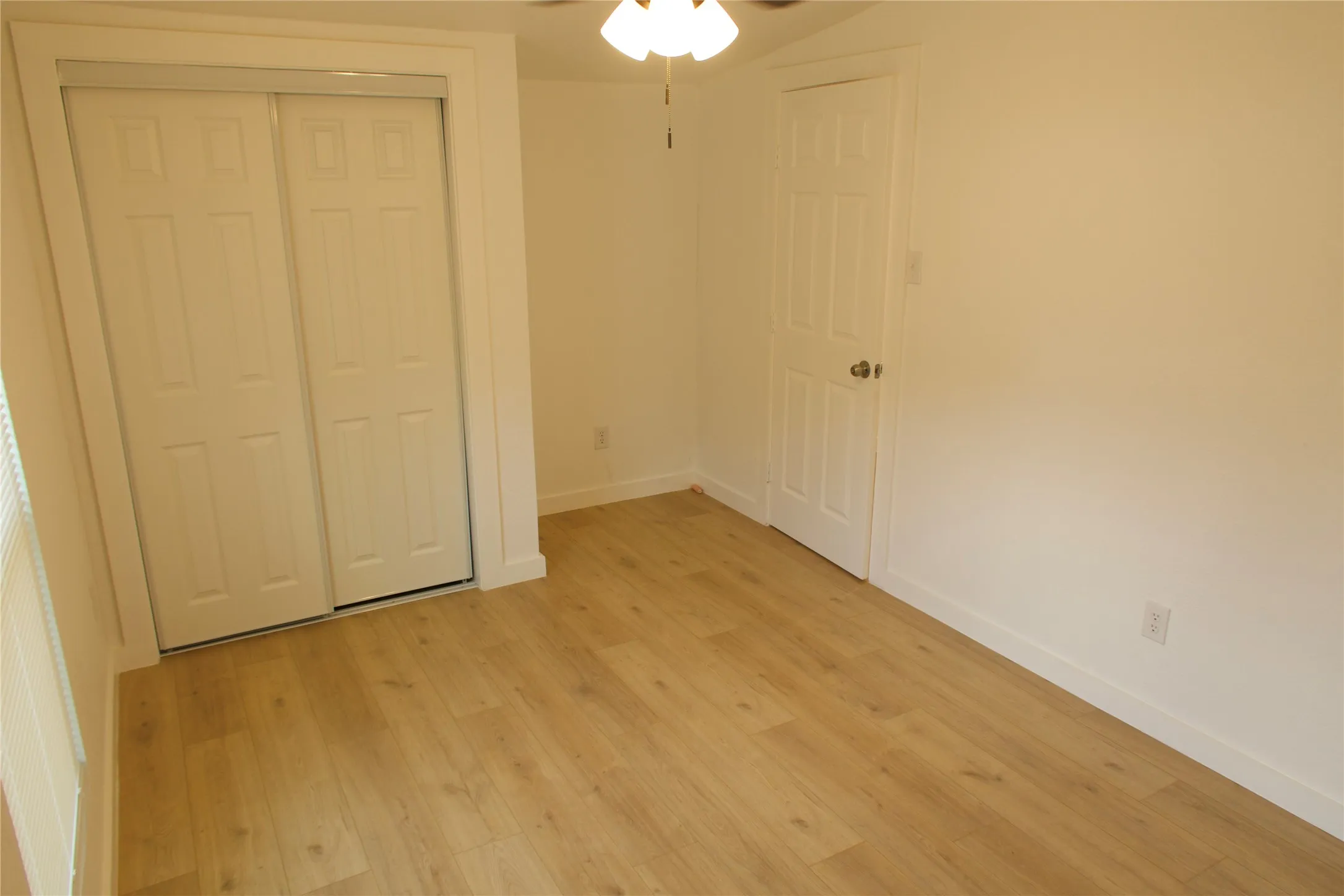 Unfurnished bedroom with light wood-type flooring, baseboards, a closet, and a ceiling fan