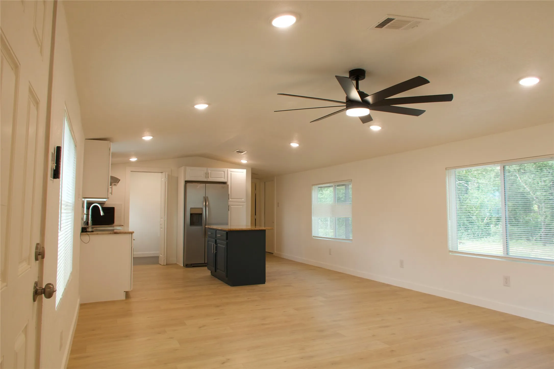 Unfurnished living room with vaulted ceiling, ceiling fan, light wood-style flooring, healthy amount of natural light, and recessed lighting