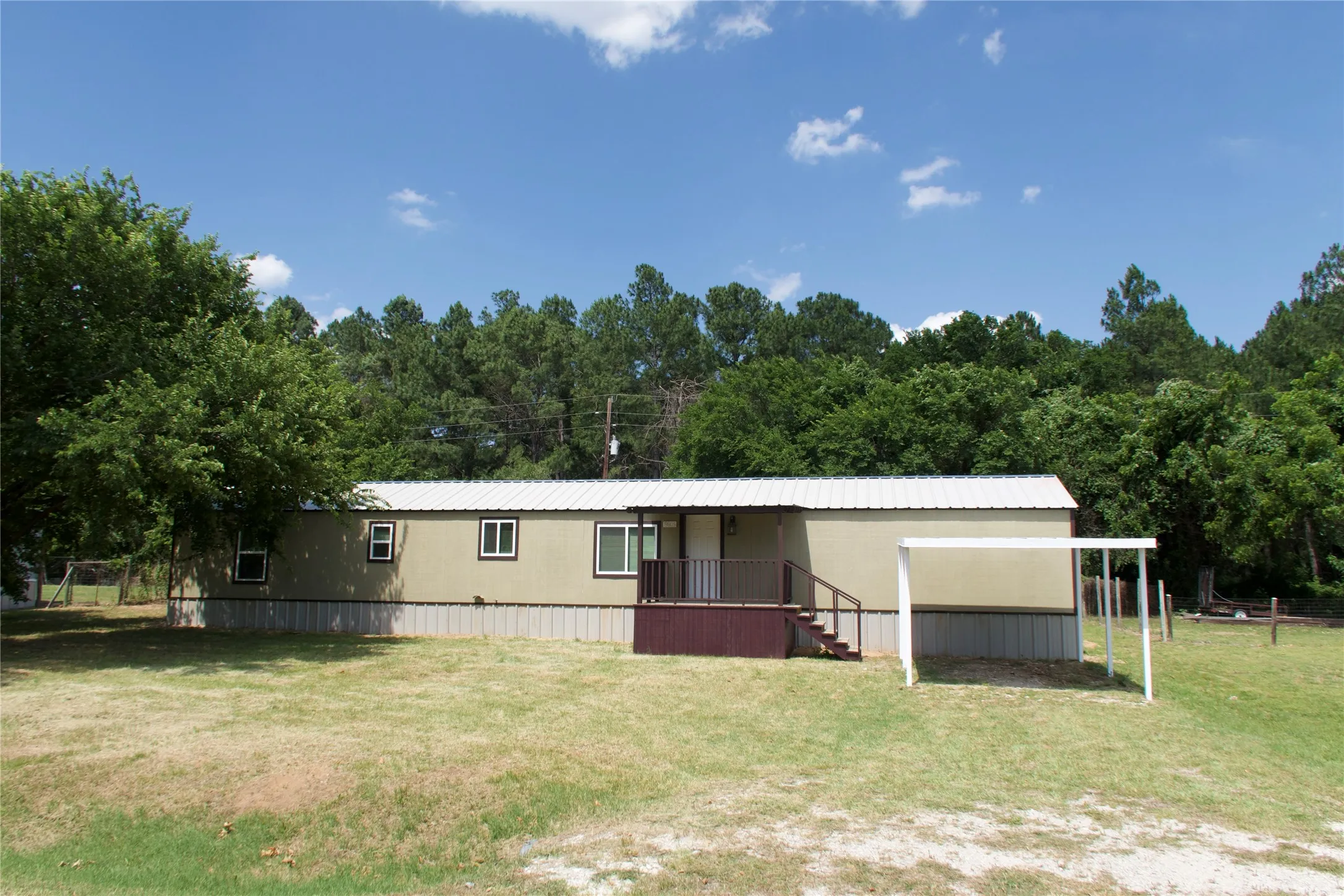 View of front facade featuring a front yard and a detached carport
