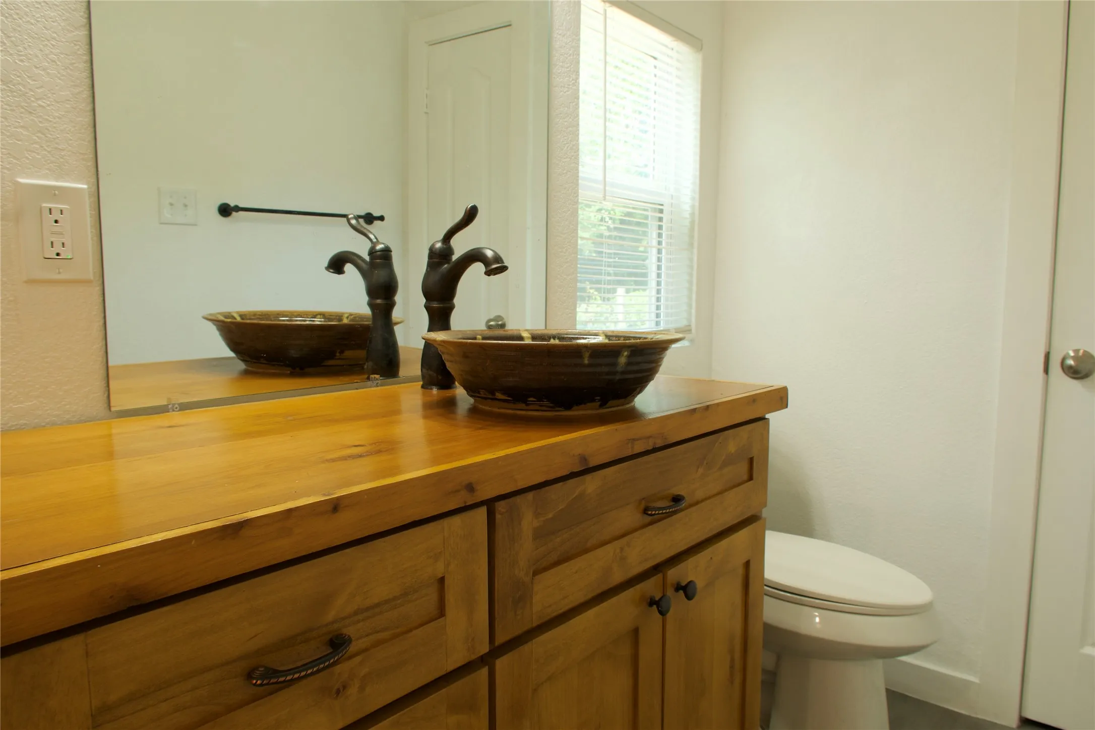 Bathroom featuring vanity, toilet, and a textured wall