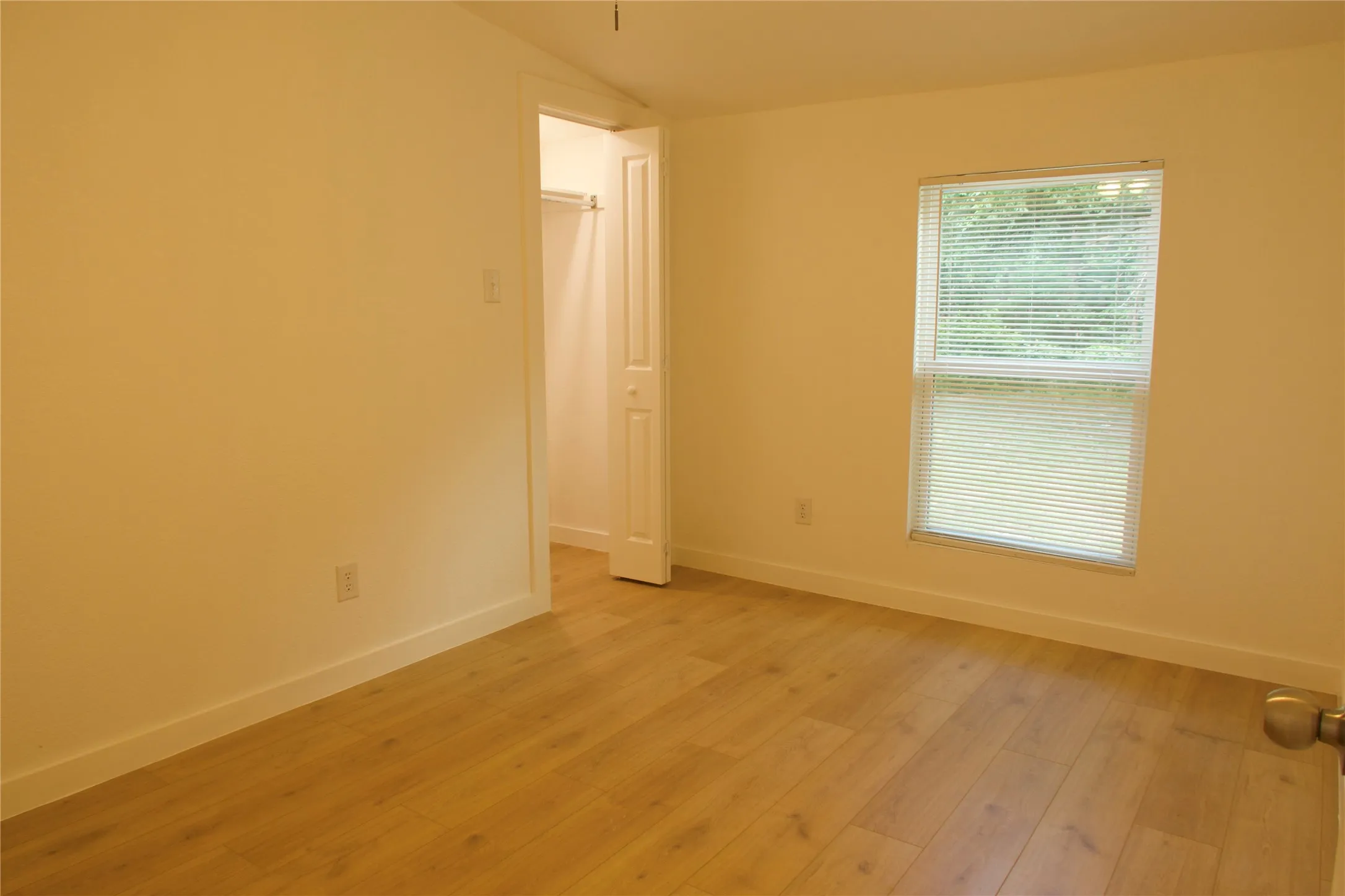 Spare room featuring lofted ceiling, light wood-style floors, and baseboards