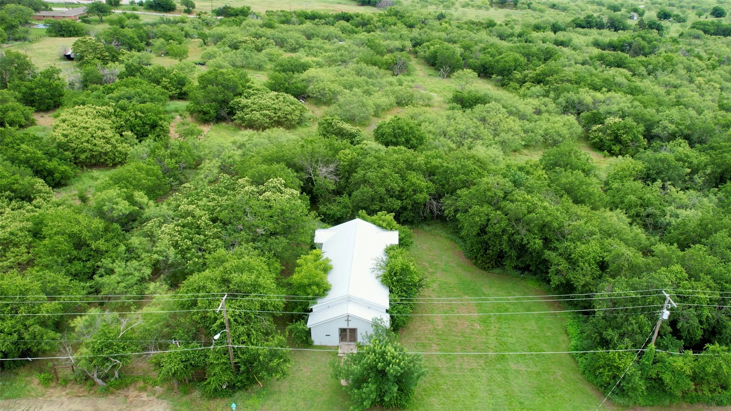 Aerial view of property and surrounding area featuring a forest
