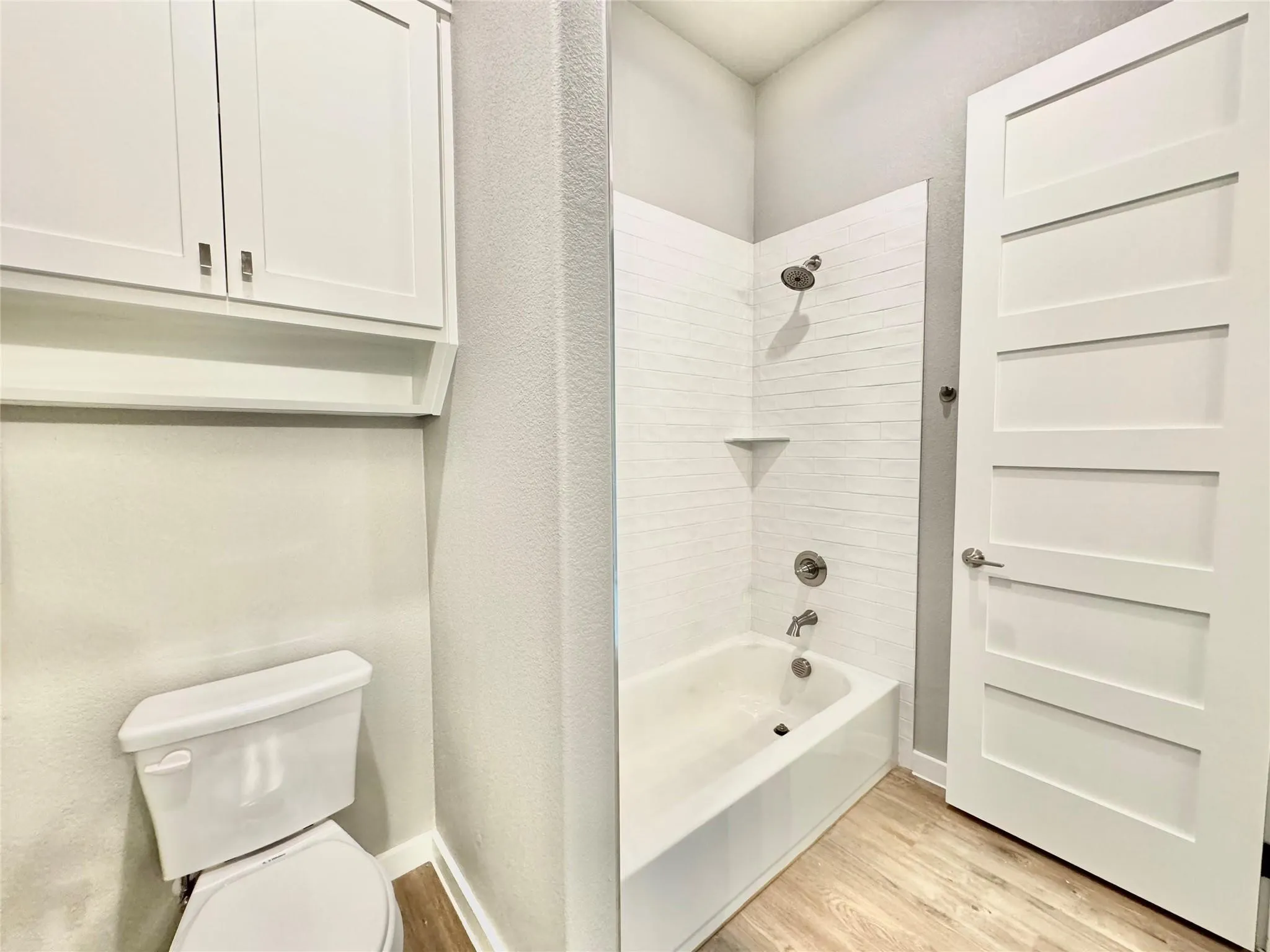 Full bath with wood finished floors, toilet, and bathing tub / shower combination