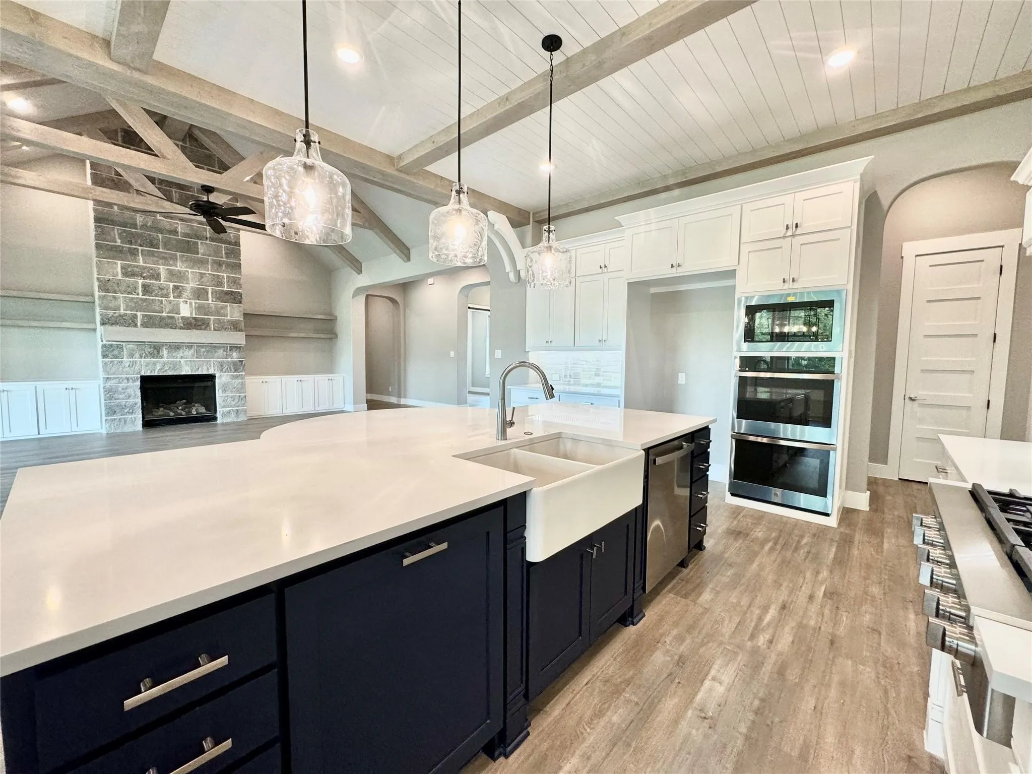 Kitchen featuring a ceiling fan, arched walkways, a sink, appliances with stainless steel finishes, and white cabinets