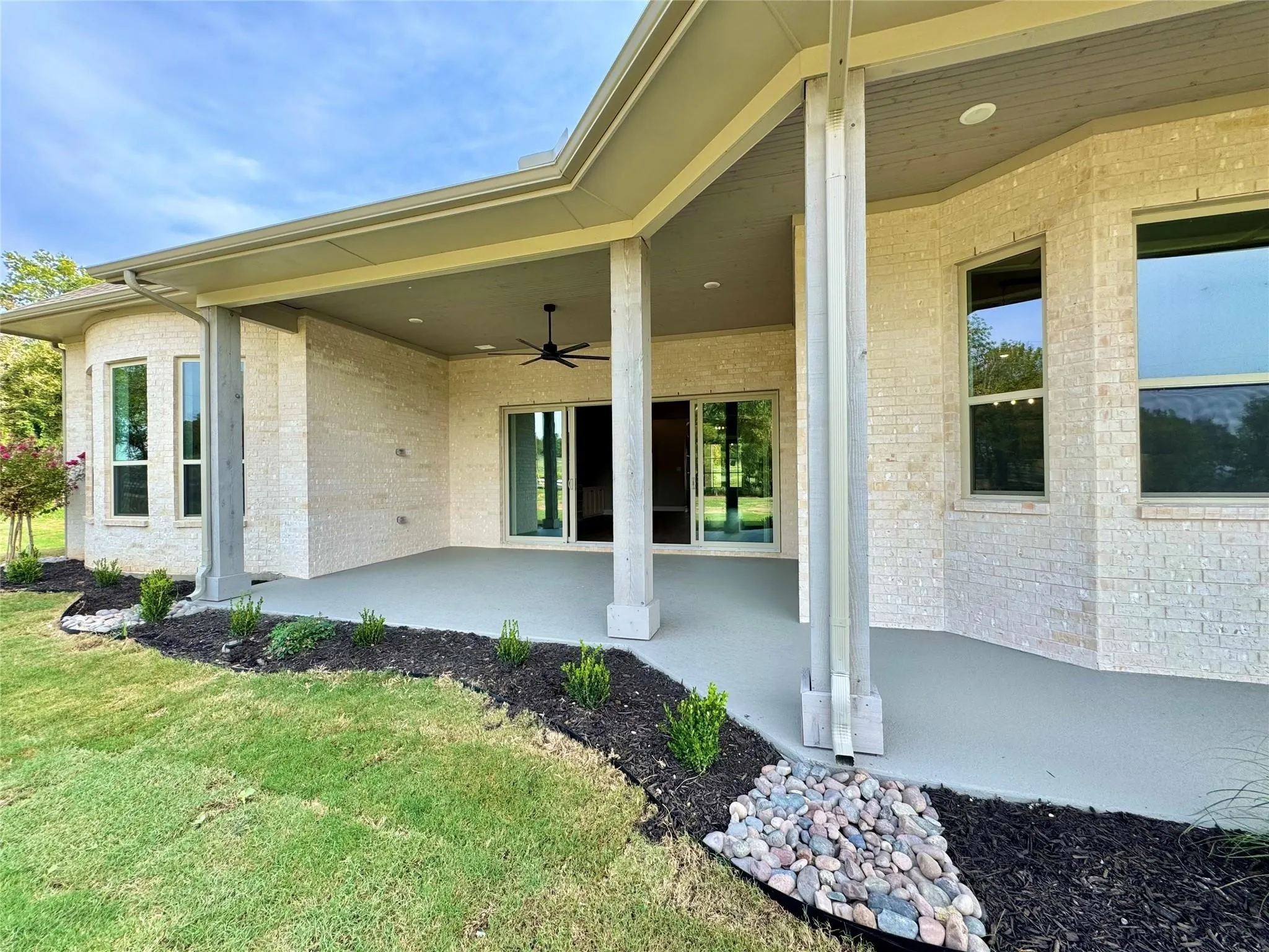 Property entrance featuring a ceiling fan, a patio, brick siding, and a lawn