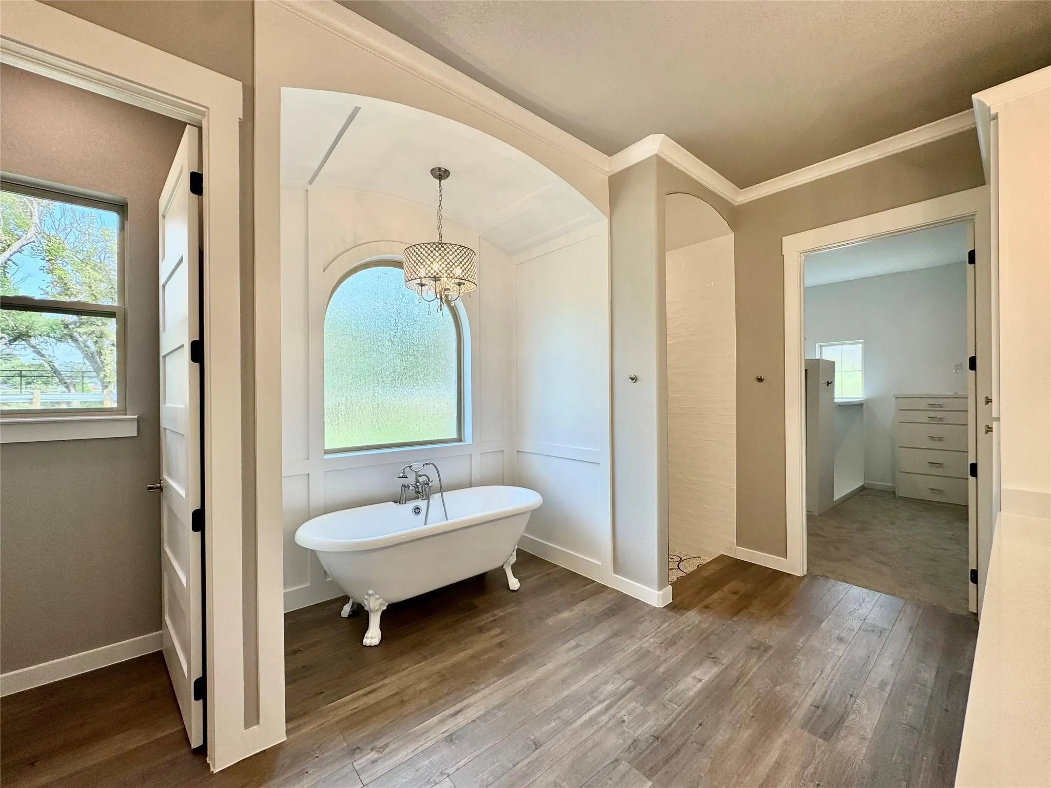 Full bath featuring a freestanding bath, wood-type flooring, a chandelier, baseboards, and crown molding