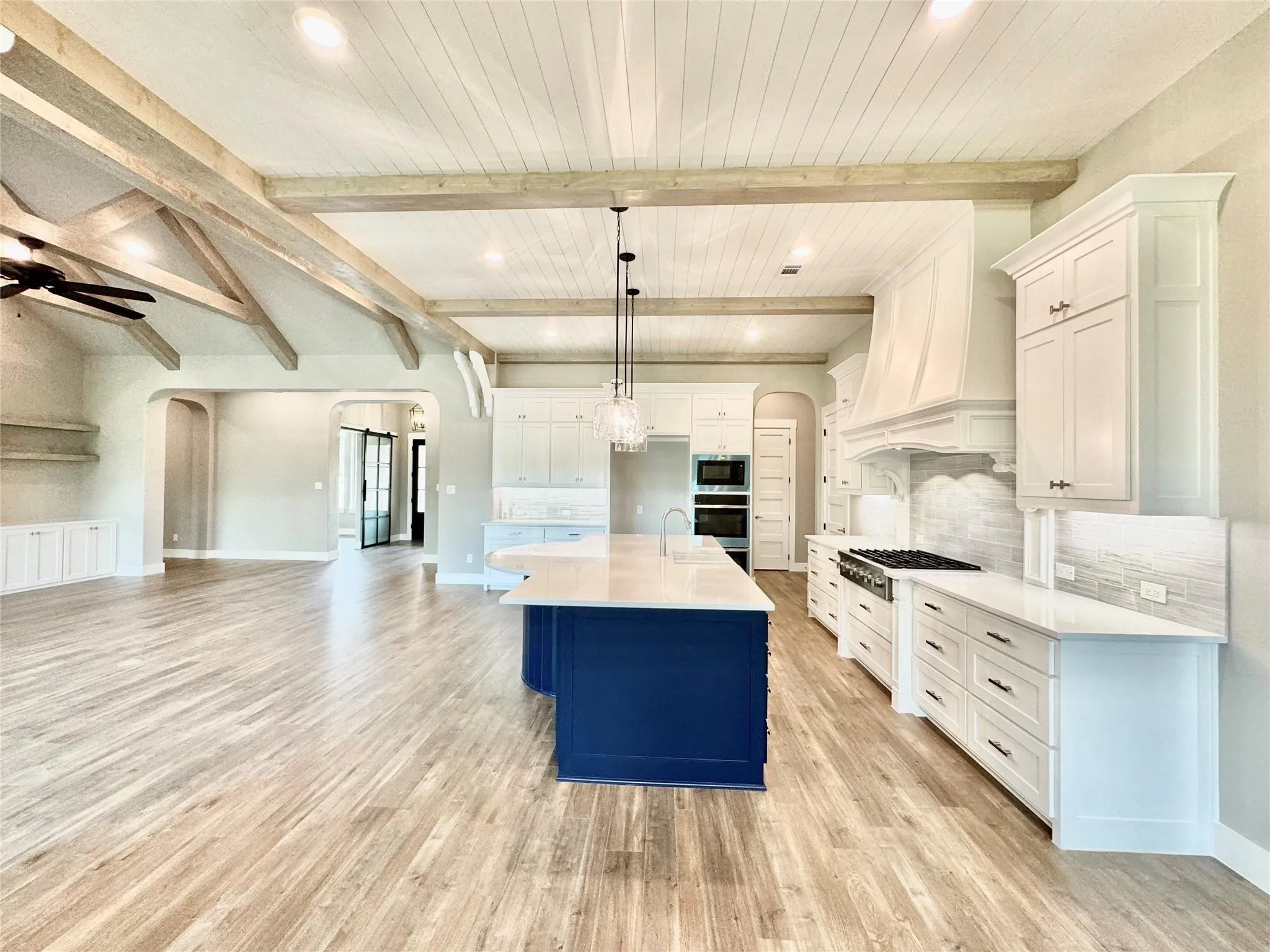 Kitchen with arched walkways, stainless steel appliances, light wood finished floors, open floor plan, and recessed lighting