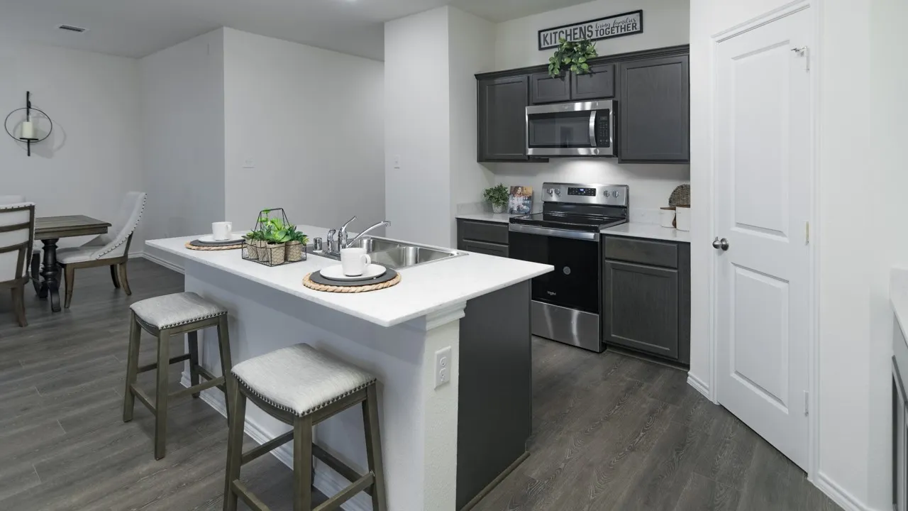 Kitchen featuring stainless steel appliances, a kitchen breakfast bar, a kitchen island with sink, and dark wood-style floors