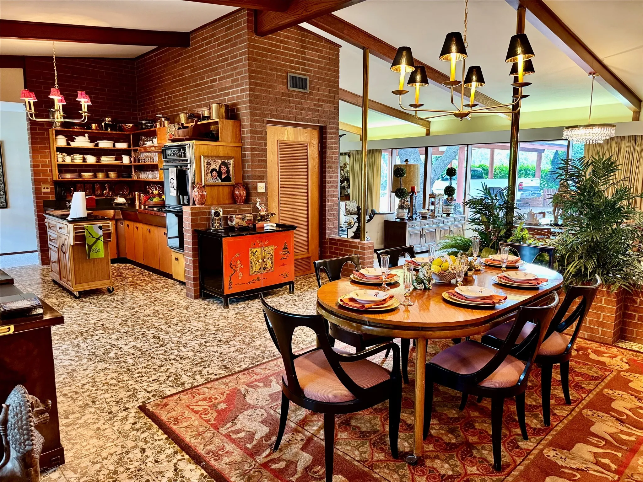 Dining space featuring a chandelier, brick wall, beam ceiling, and a towering ceiling