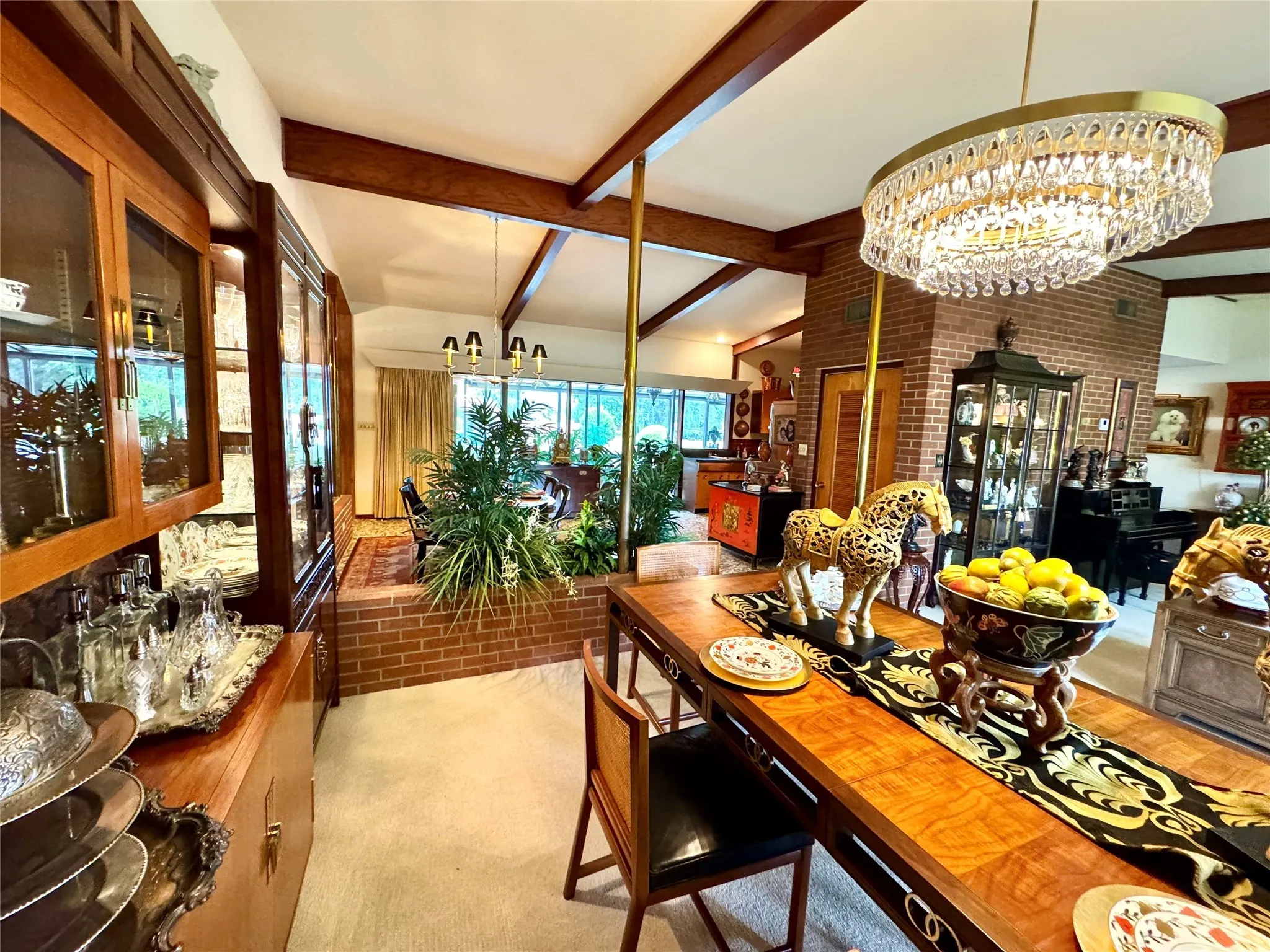 Dining room with a chandelier, beam ceiling, brick wall, and brick patterned floors