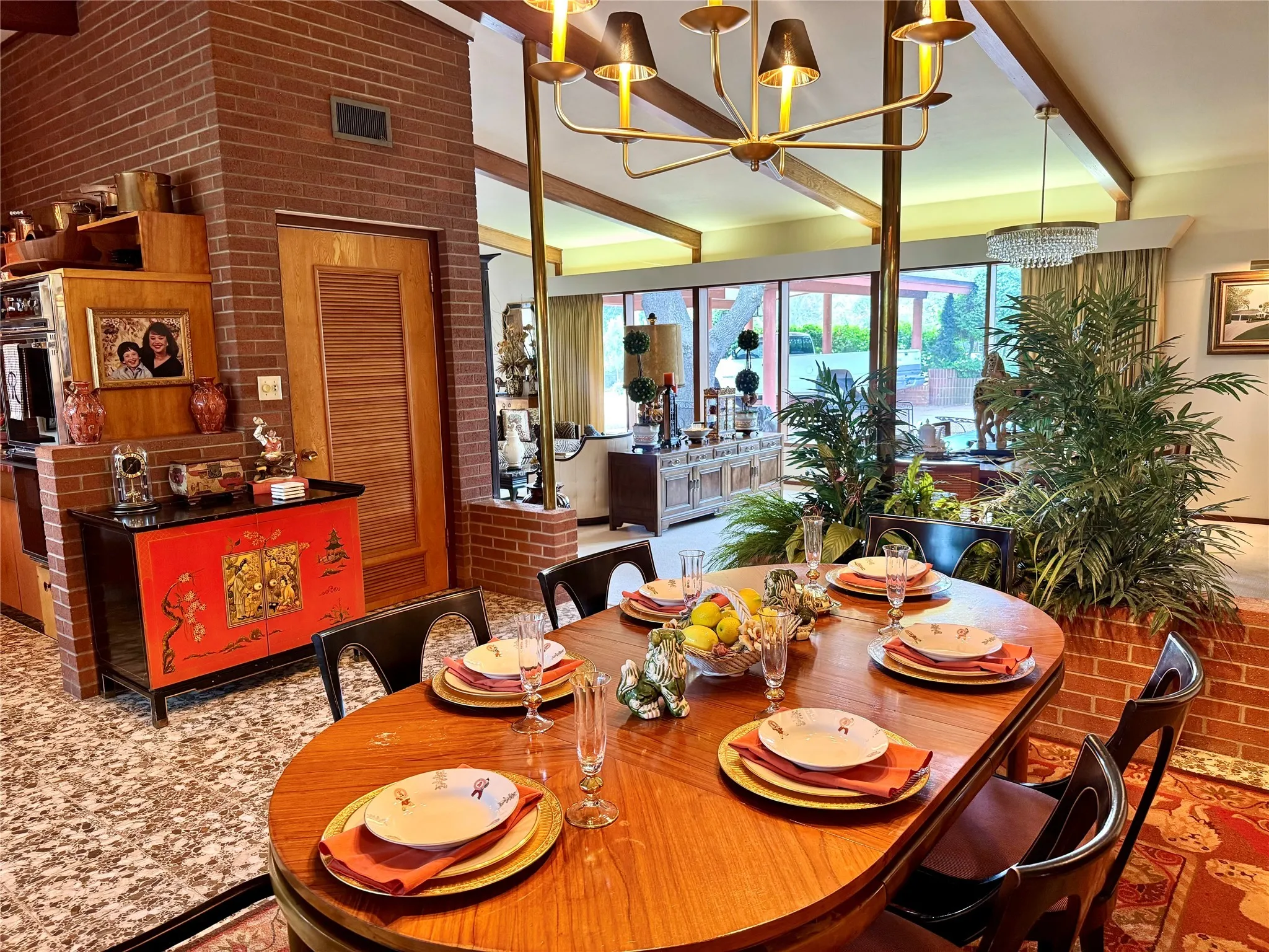 Dining area with brick wall, beam ceiling, and a chandelier