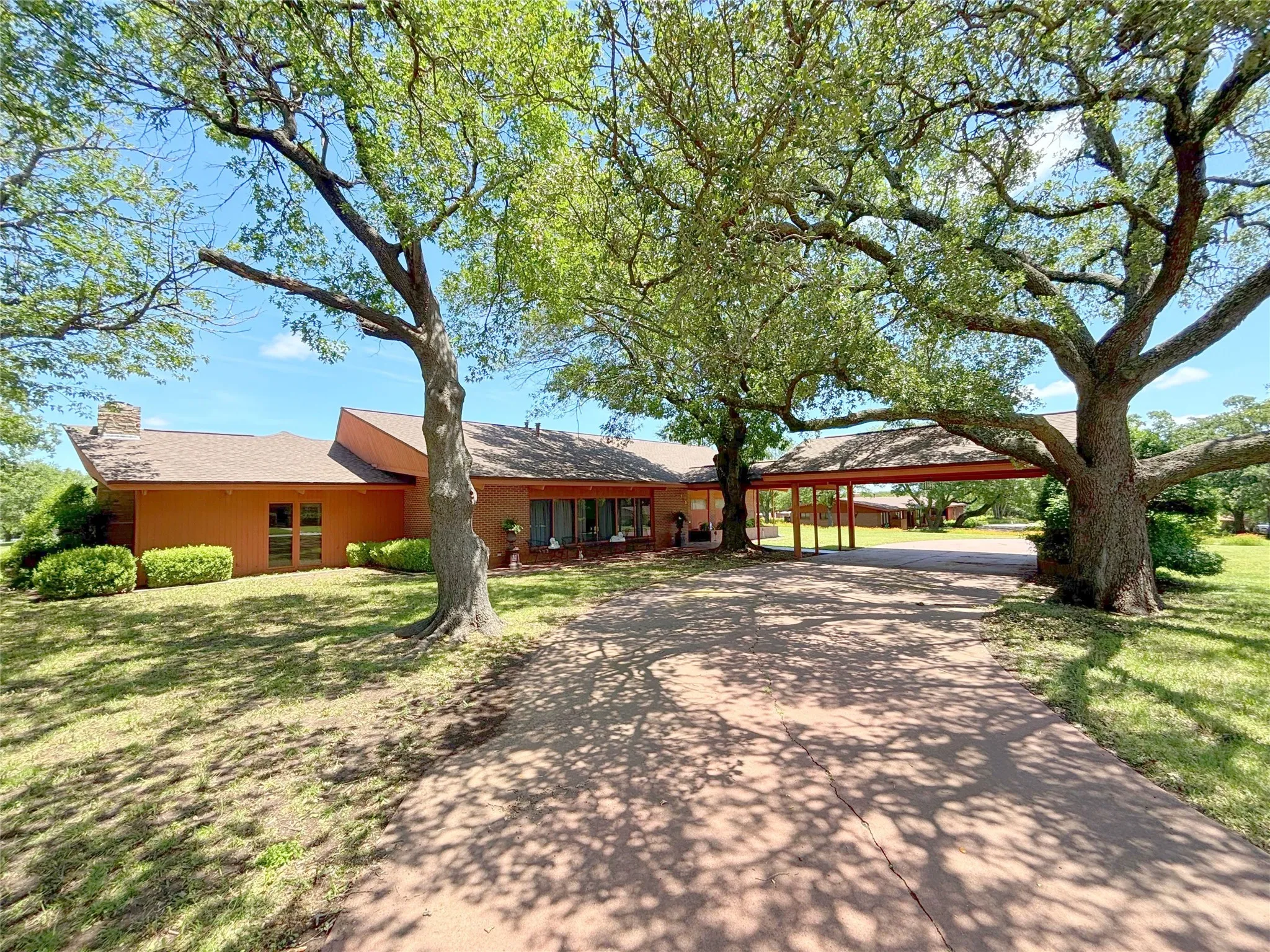 Ranch-style home with driveway, a chimney, a front lawn, and a carport
