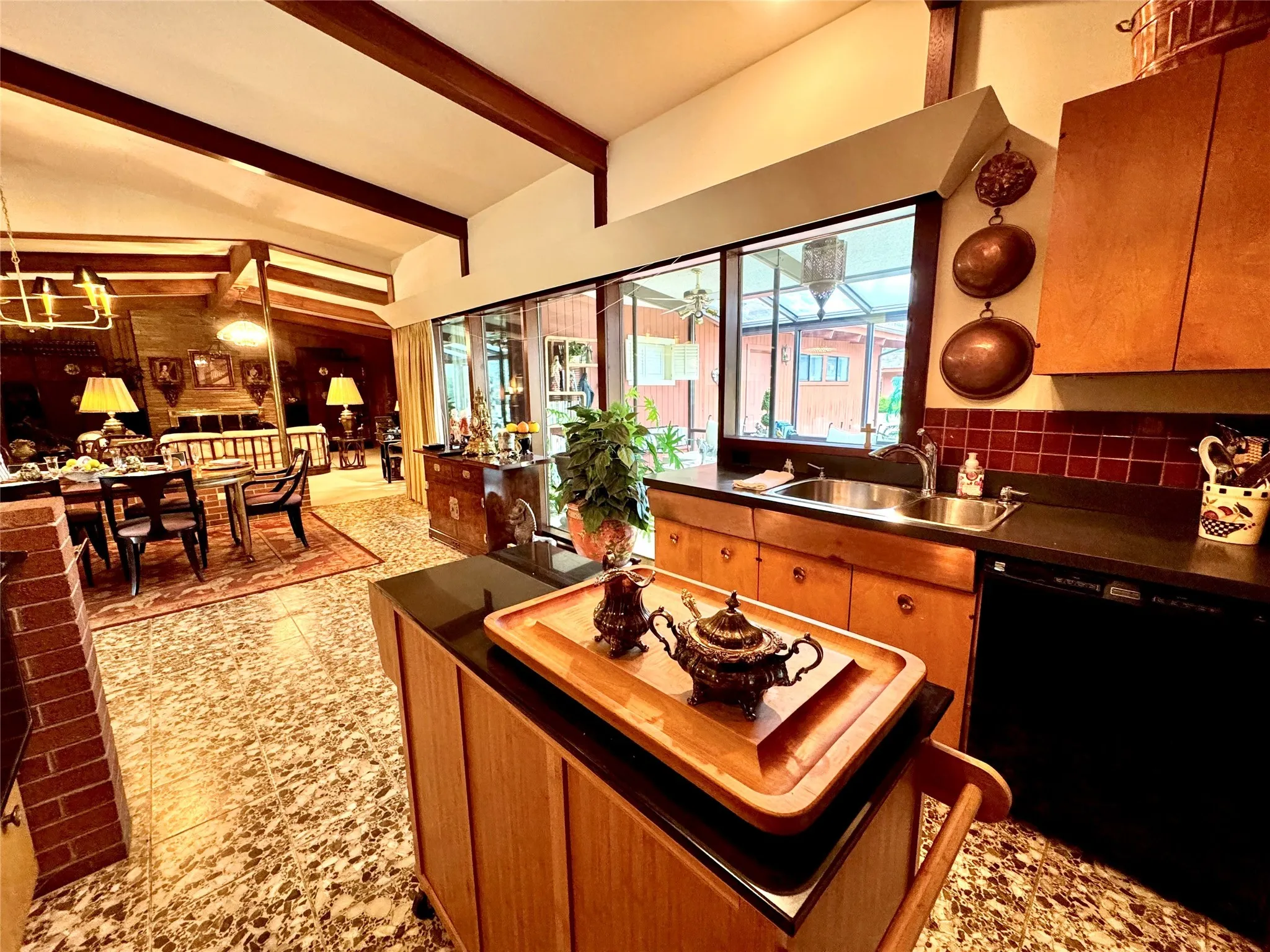 Kitchen with dark countertops, brown cabinets, black dishwasher, and backsplash