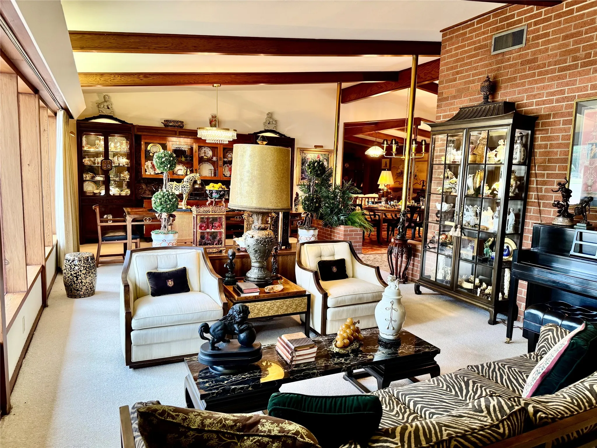 Living area featuring beamed ceiling, brick wall, and carpet floors