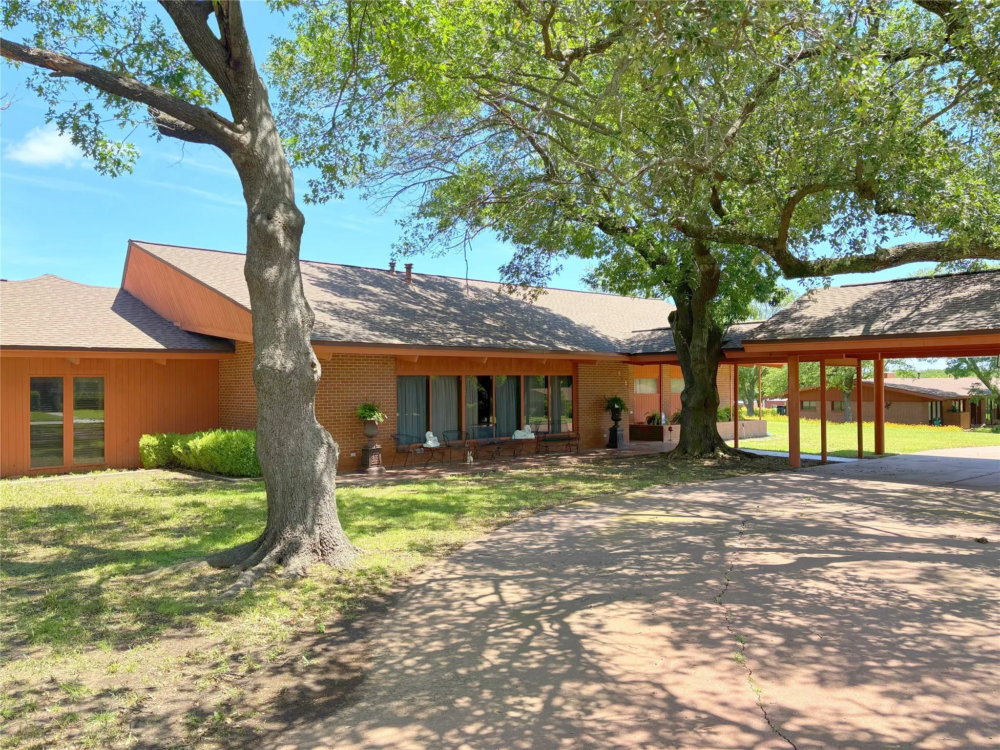 View of front of home featuring concrete driveway, a front yard, brick siding, and a carport
