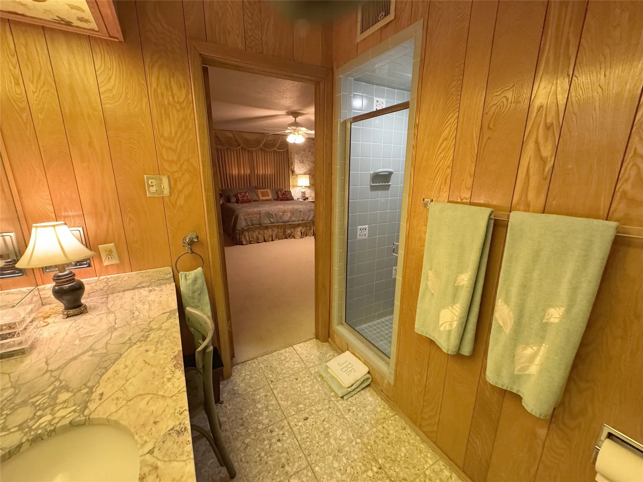 Full bath featuring wood walls, a shower stall, double vanity, ensuite bathroom, and ceiling fan