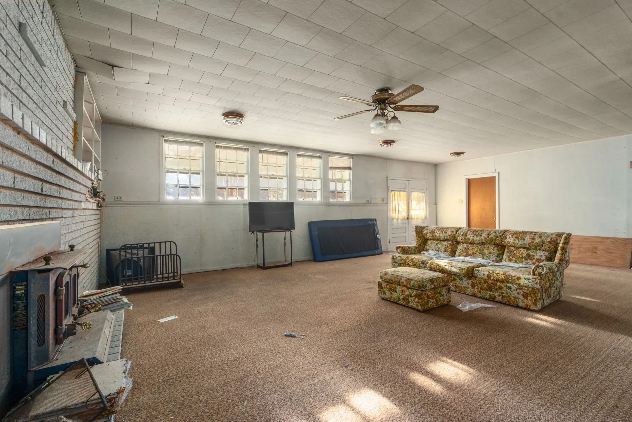 Living room with a wood stove, a ceiling fan, and carpet floors