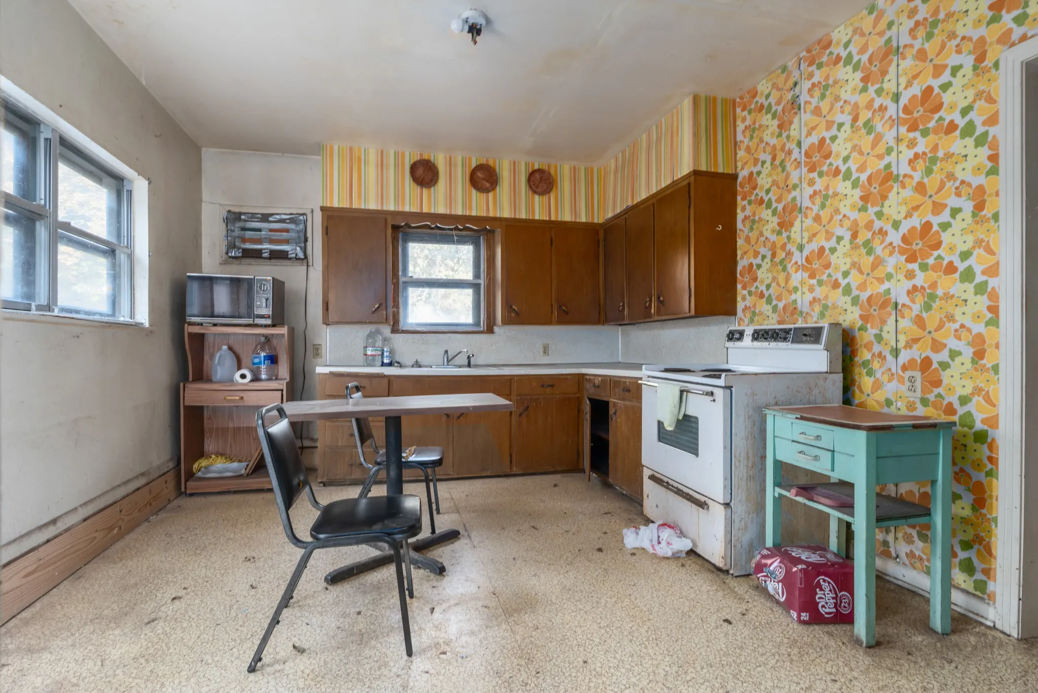 Kitchen featuring white range with electric cooktop, light floors, light countertops, wallpapered walls, and black microwave