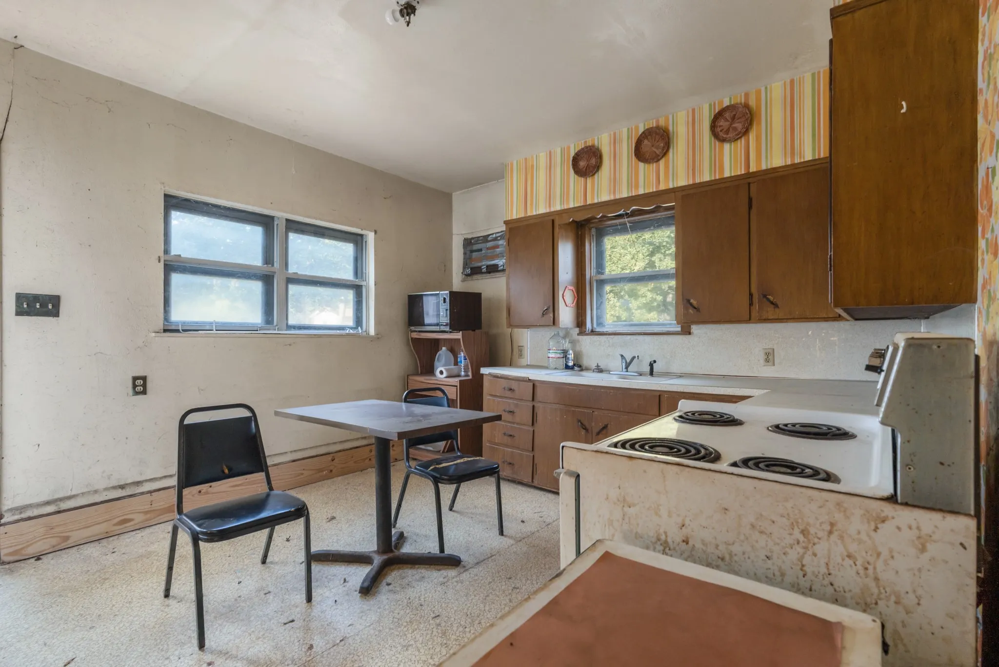 Kitchen featuring light countertops, brown cabinetry, electric stove, and black microwave