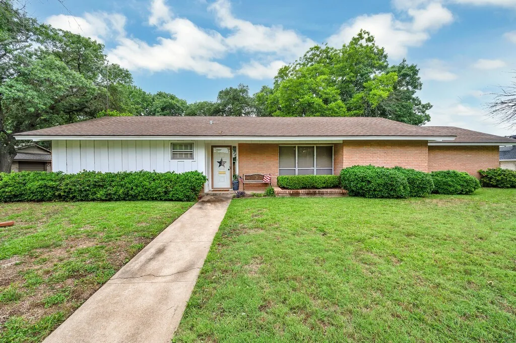 Ranch-style house with a front yard, brick siding, and a shingled roof