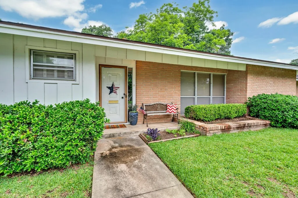 Doorway to property with a porch, brick siding, board and batten siding, and a yard