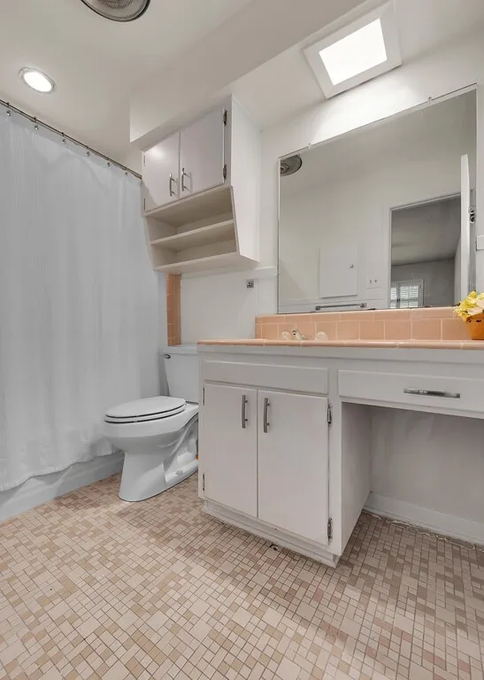 Bathroom featuring toilet, vanity, and shower / tub combo with curtain