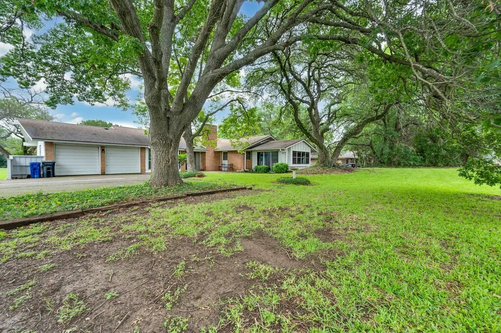 View of front of home with brick siding, a garage, driveway, and a front yard