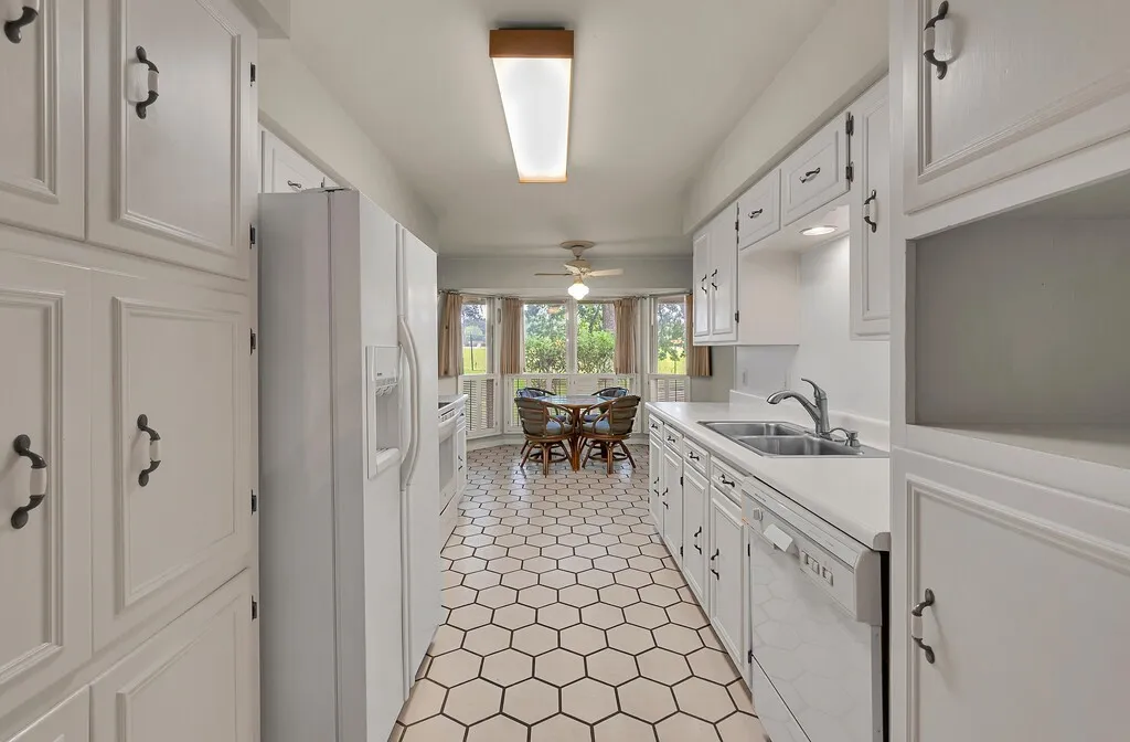 Kitchen featuring white appliances, a sink, light countertops, and white cabinetry