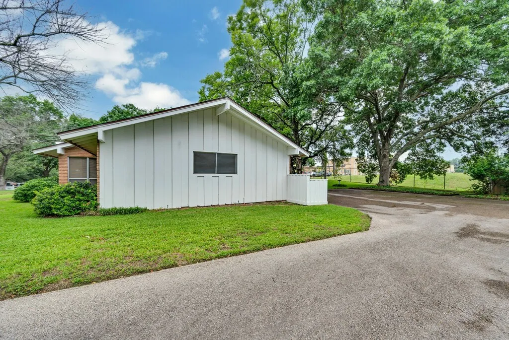 View of side of home featuring board and batten siding, a yard, and driveway