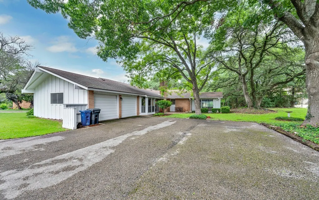 View of front of house featuring asphalt driveway, an attached garage, board and batten siding, a front lawn, and a chimney