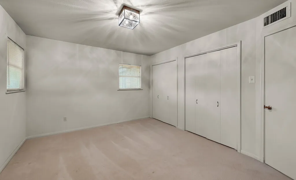 Unfurnished bedroom featuring multiple closets, carpet floors, and baseboards