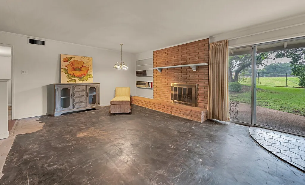 Unfurnished living room with ornamental molding, a brick fireplace, and a chandelier