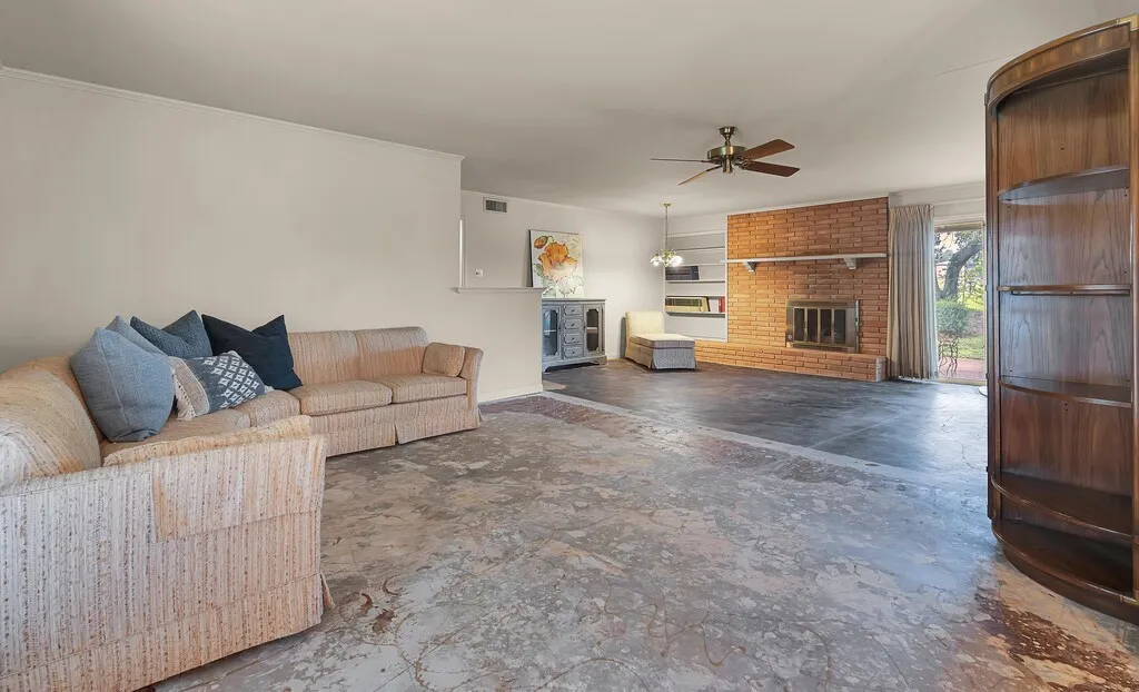 Living room featuring a ceiling fan, a brick fireplace, baseboards, and ornamental molding