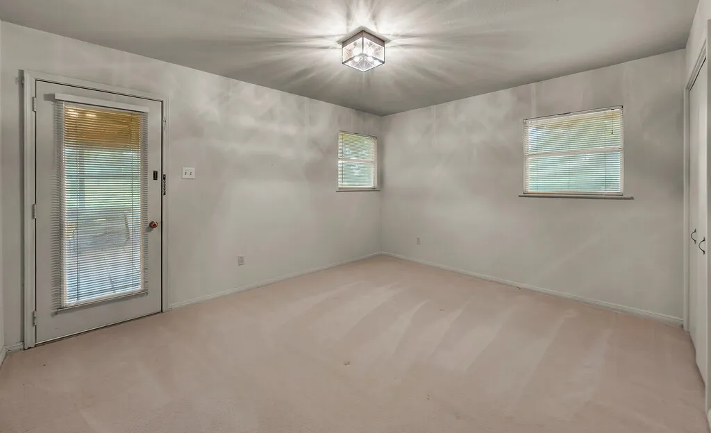 Empty room featuring light colored carpet, plenty of natural light, and baseboards