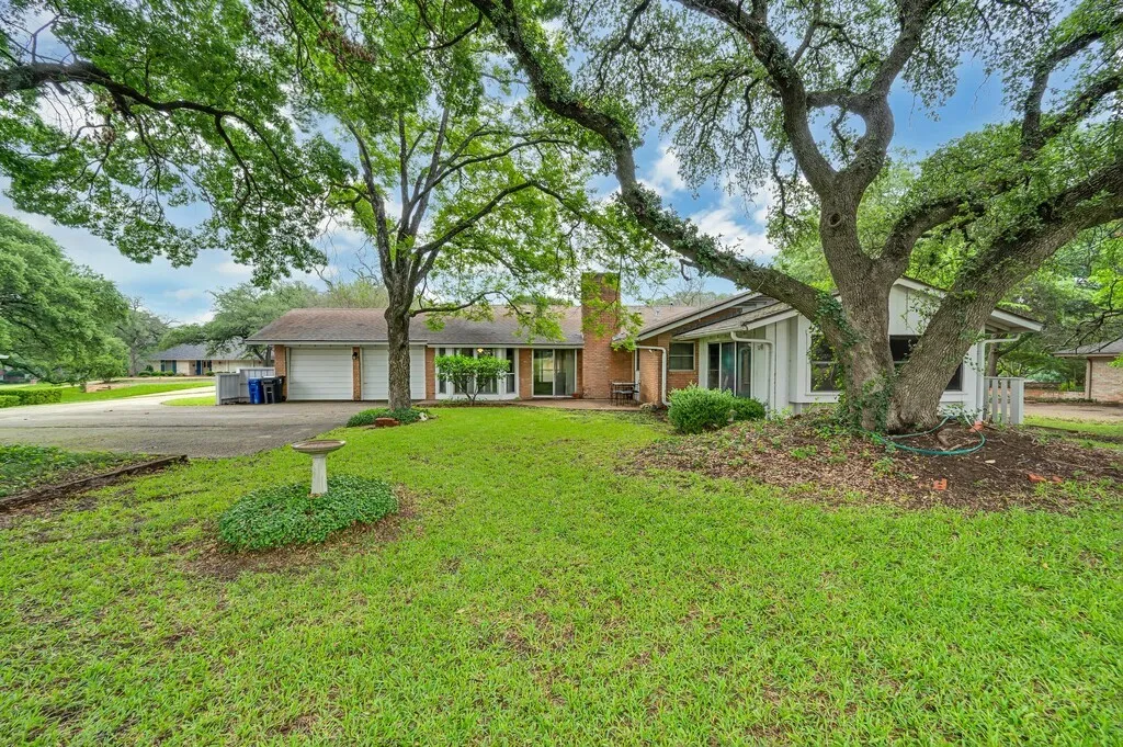 View of front facade featuring a chimney, driveway, an attached garage, and a front lawn