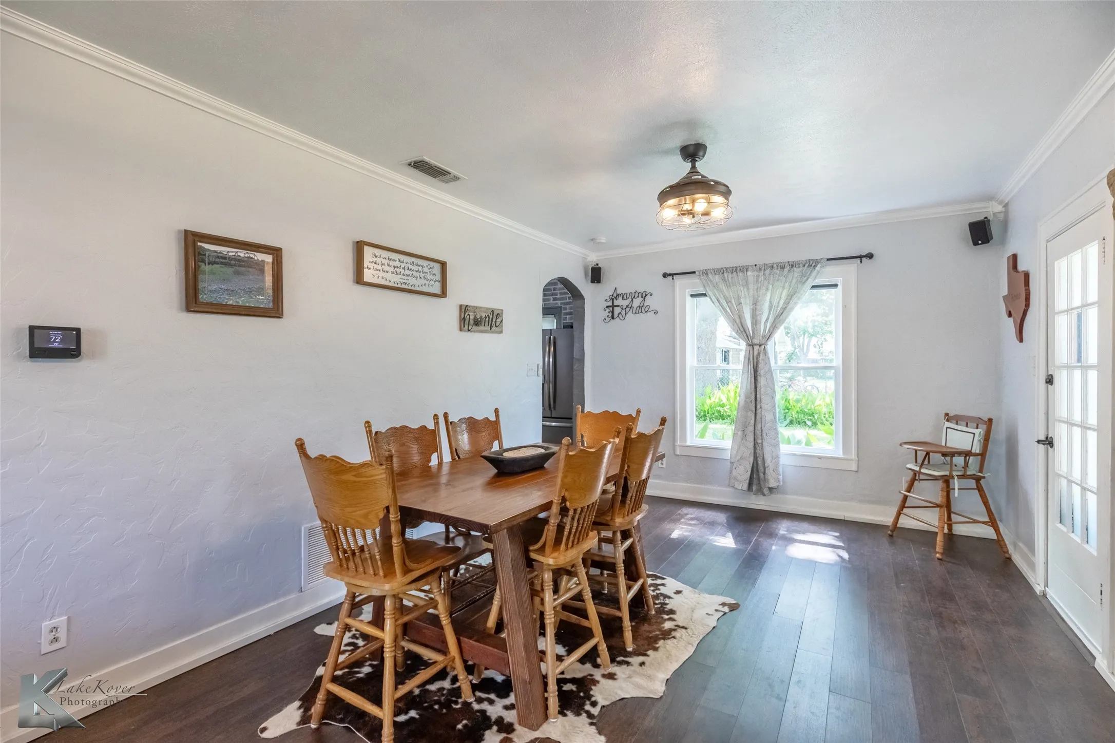 Dining area featuring arched walkways, healthy amount of natural light, crown molding, baseboards, and dark wood-style floors