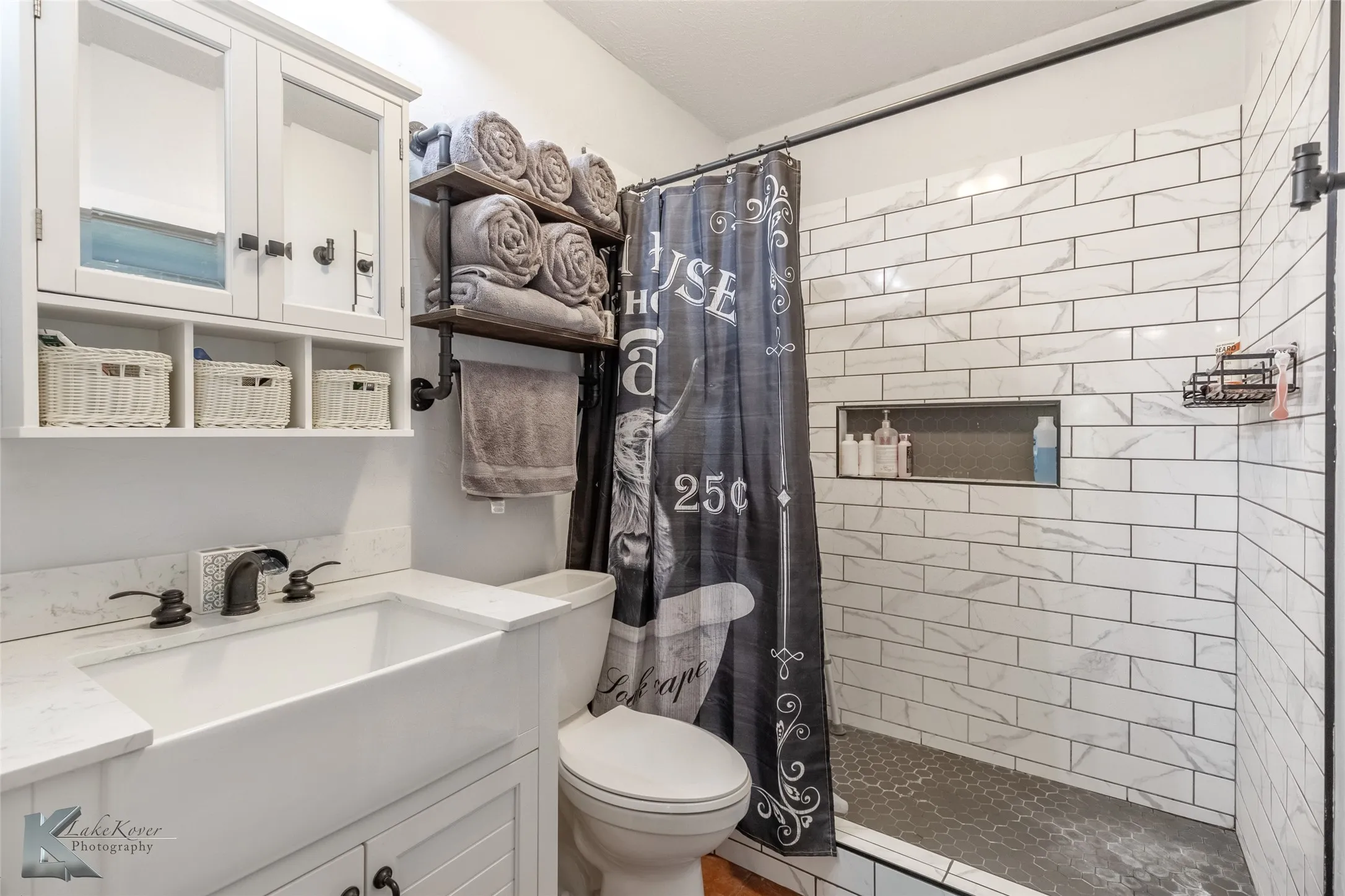 Full bath featuring toilet, tiled shower, and vanity