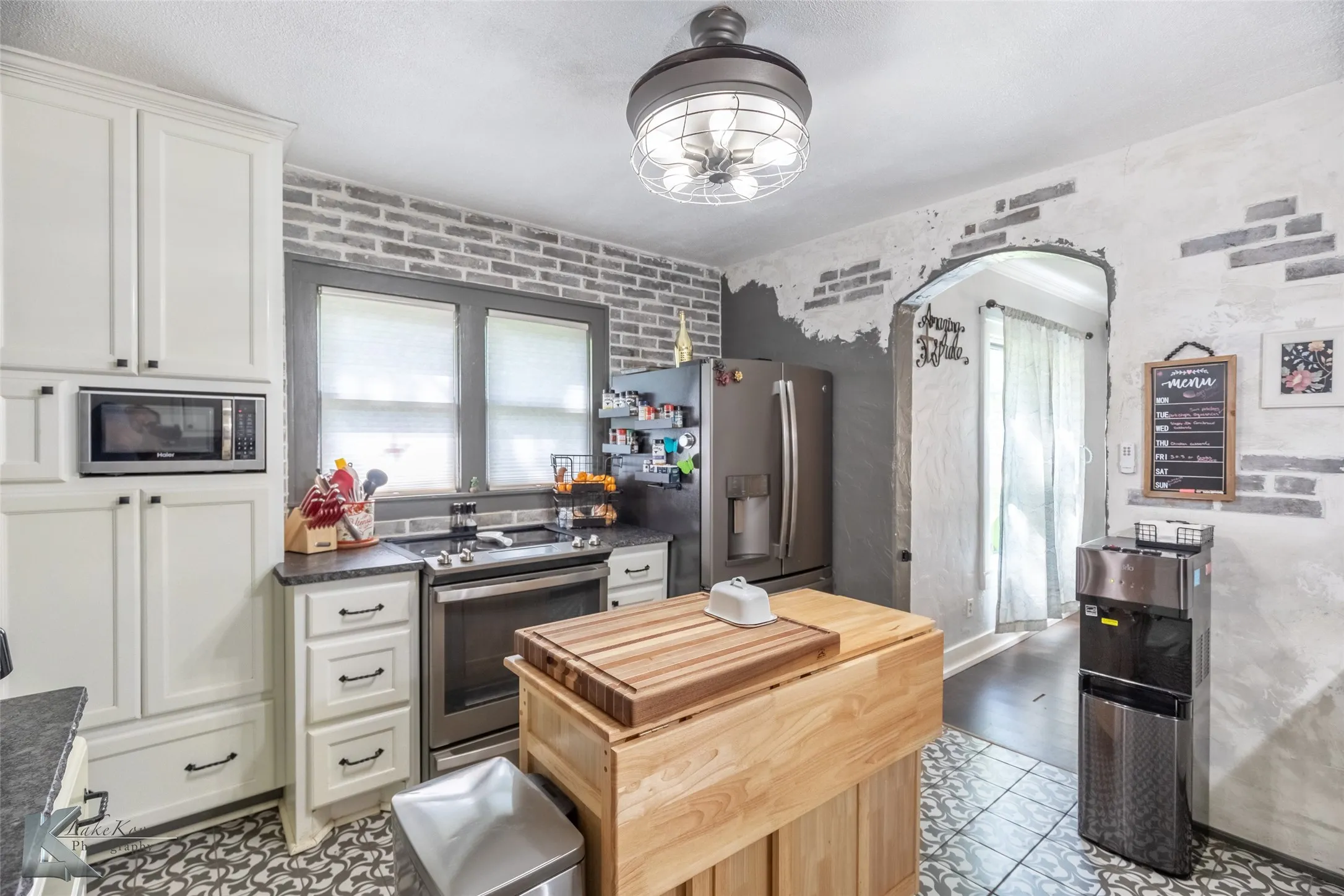 Kitchen featuring stainless steel appliances, white cabinetry, arched walkways, a kitchen island, and butcher block countertops