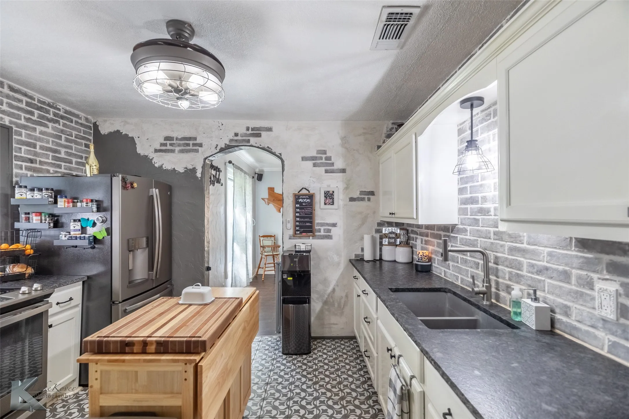 Kitchen featuring a sink, stainless steel electric stove, white cabinetry, a ceiling fan, and arched walkways
