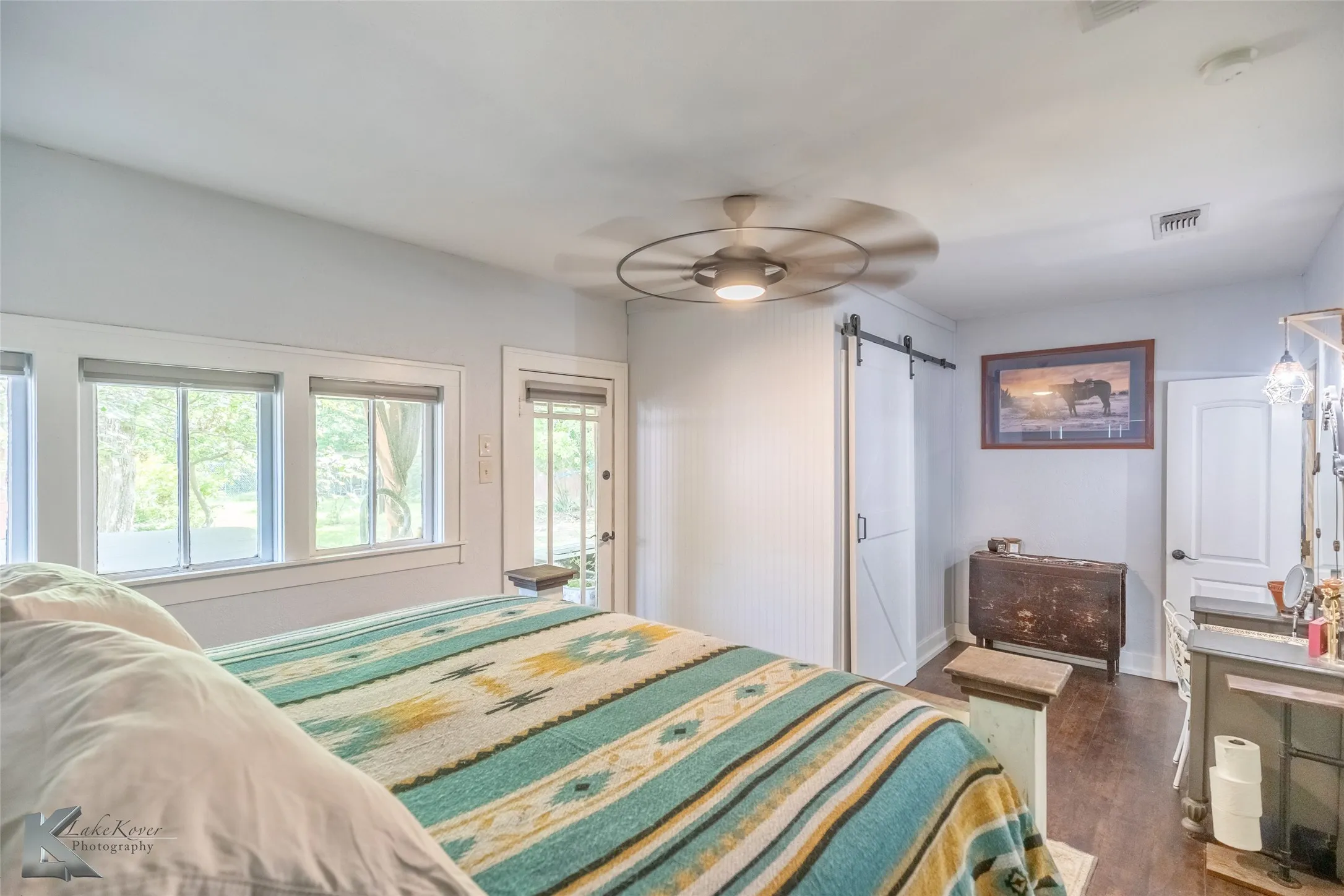 Bedroom featuring a barn door, dark wood finished floors, baseboards, access to outside, and ceiling fan
