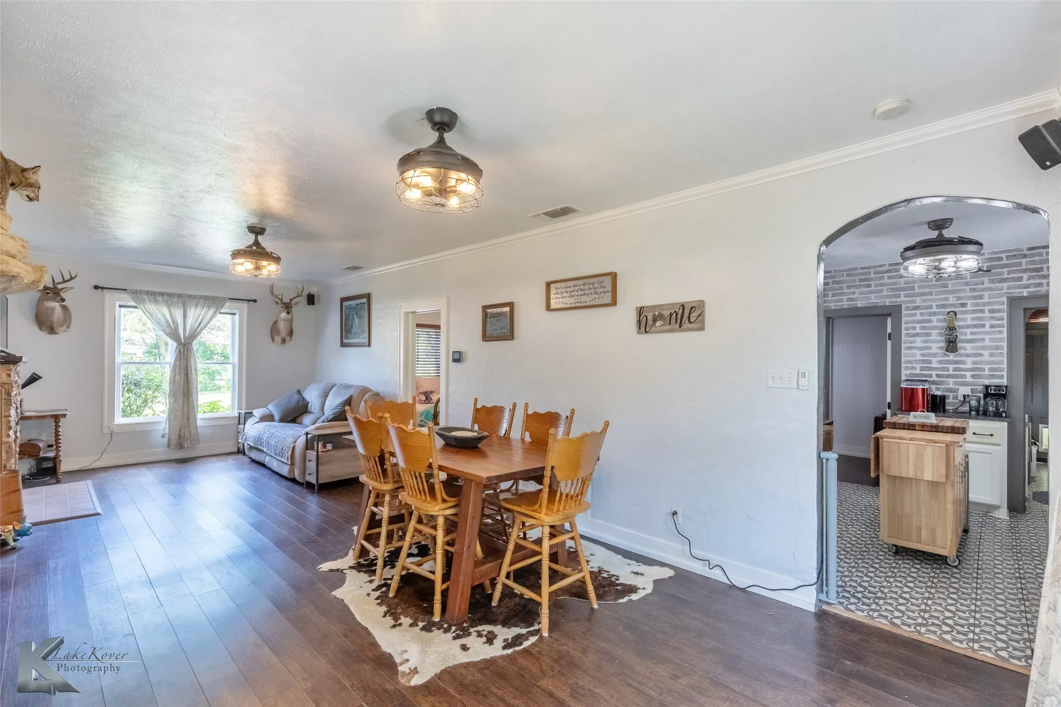 Dining space featuring dark wood-style flooring, baseboards, arched walkways, and ornamental molding