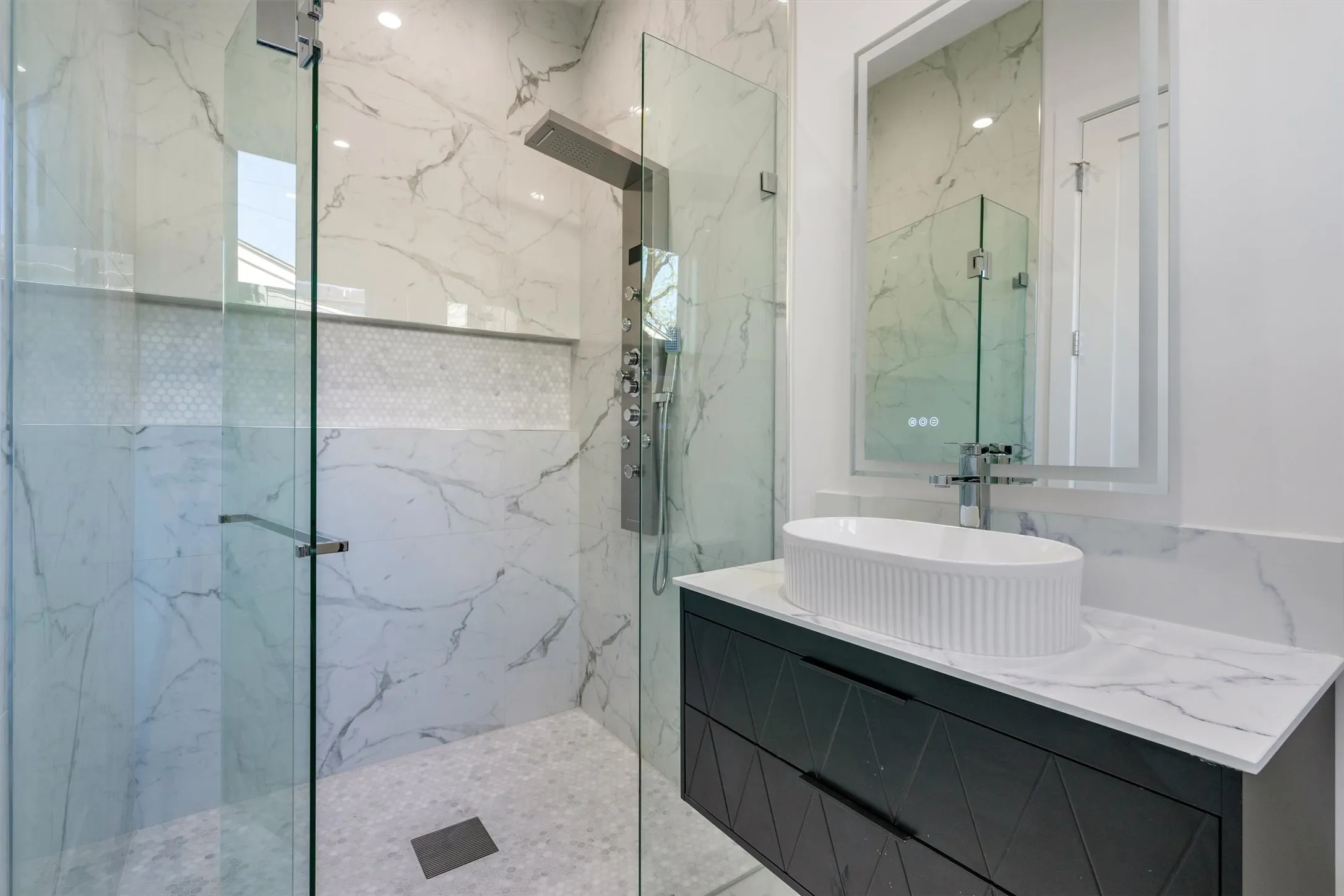Bathroom featuring a marble finish shower and vanity