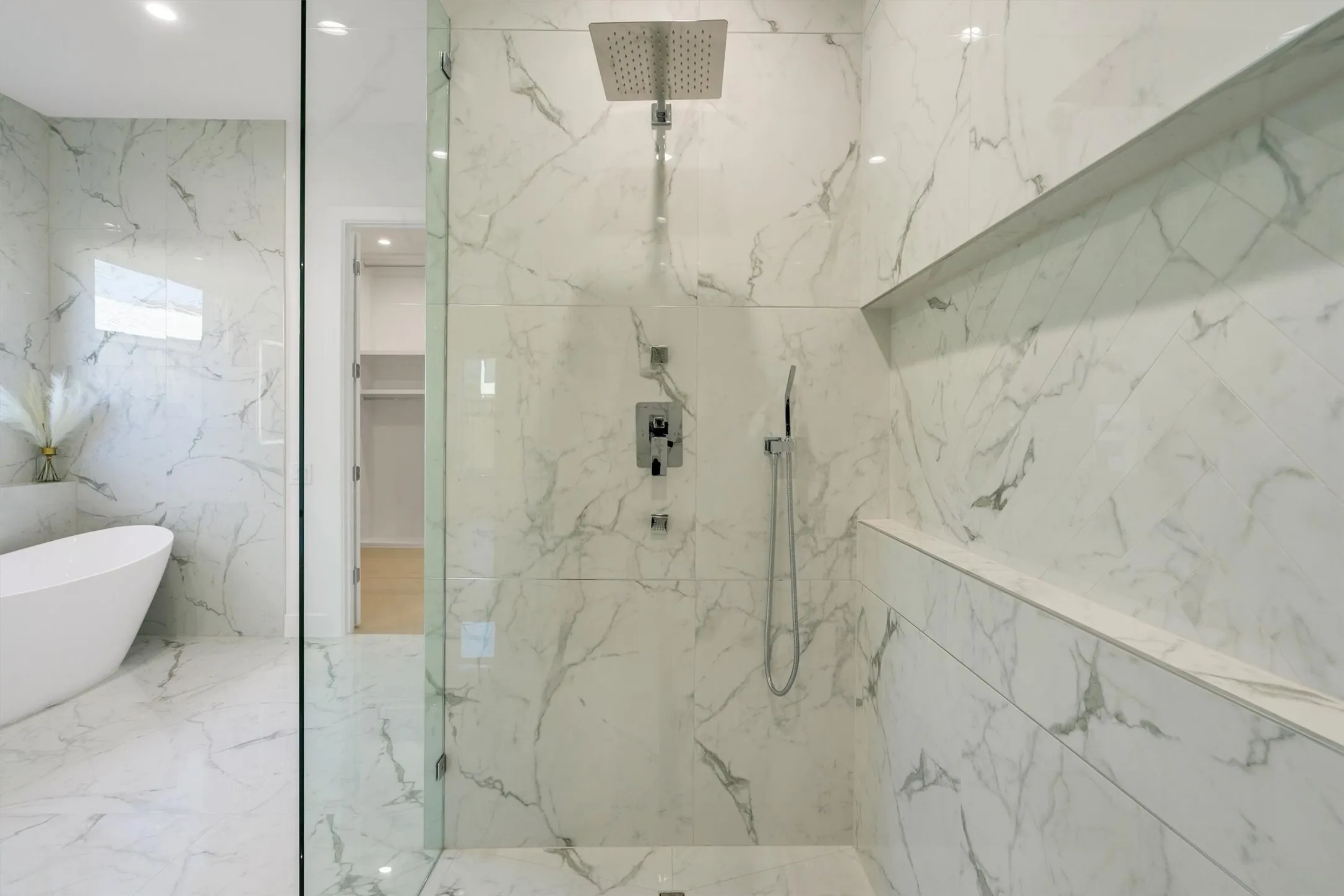 Bathroom featuring a marble finish shower, a spacious closet, a freestanding bath, and recessed lighting
