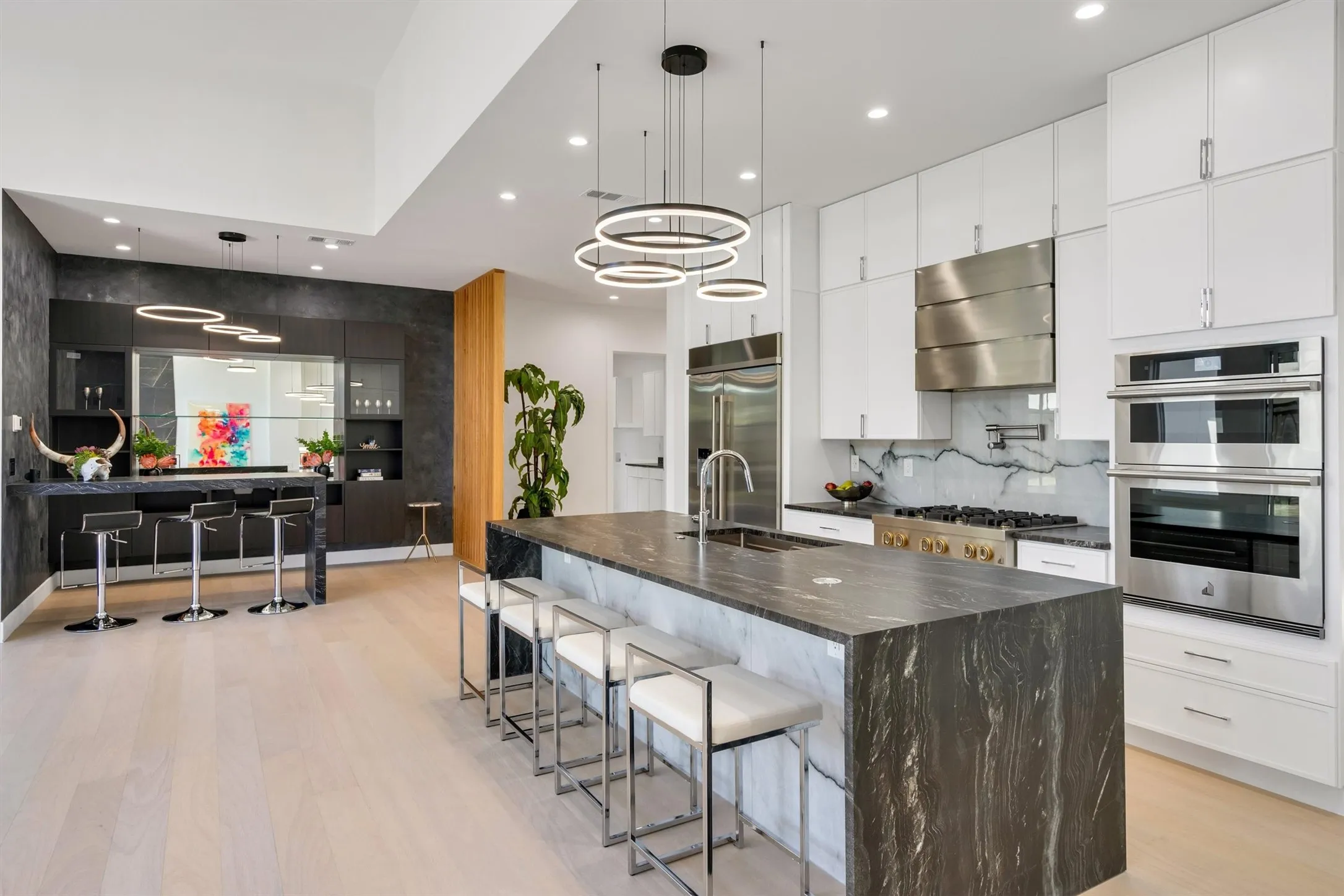 Kitchen featuring a sink, stainless steel appliances, exhaust hood, light wood-style flooring, and recessed lighting