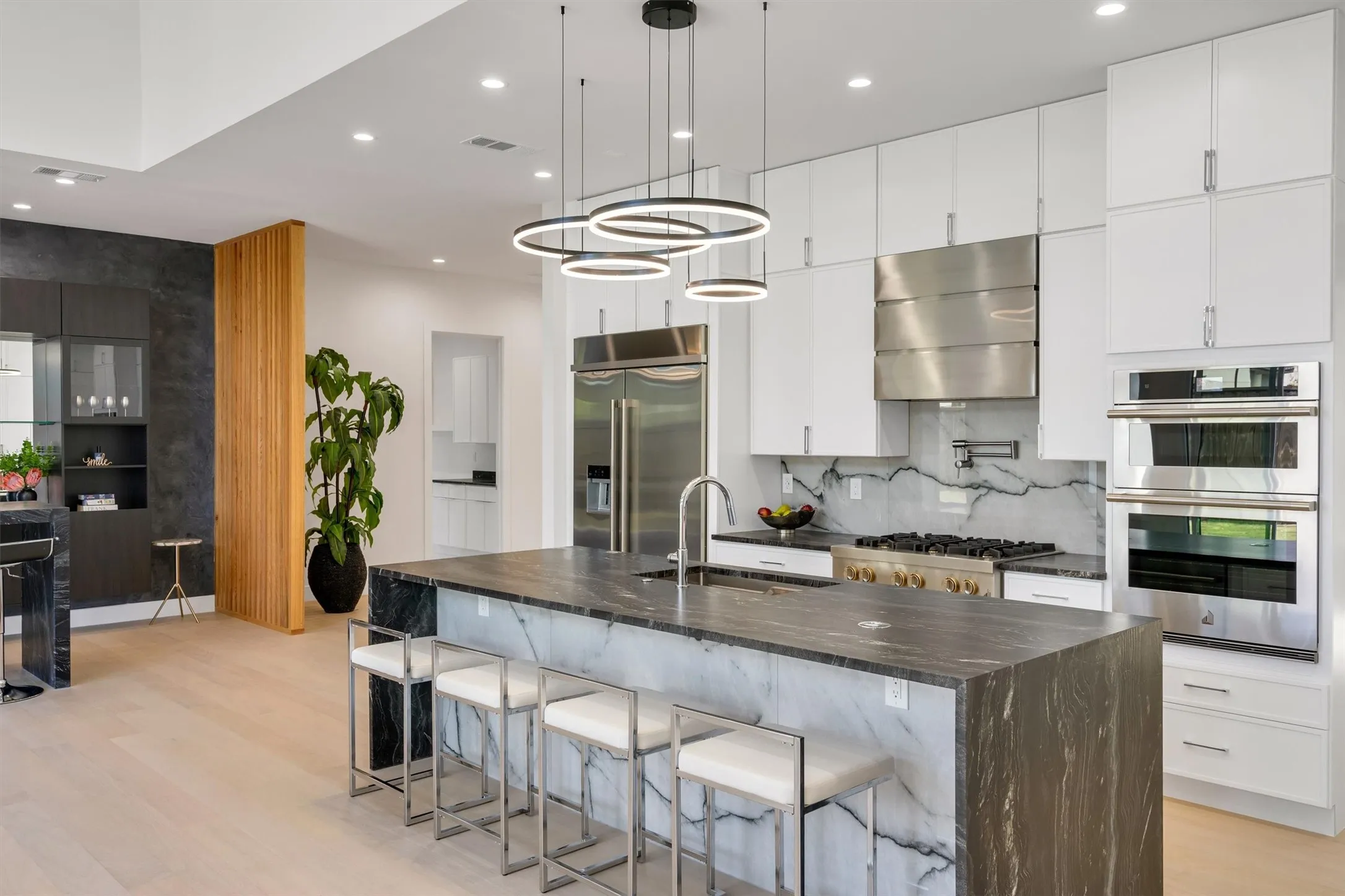 Kitchen with a sink, exhaust hood, appliances with stainless steel finishes, light wood-style flooring, and recessed lighting
