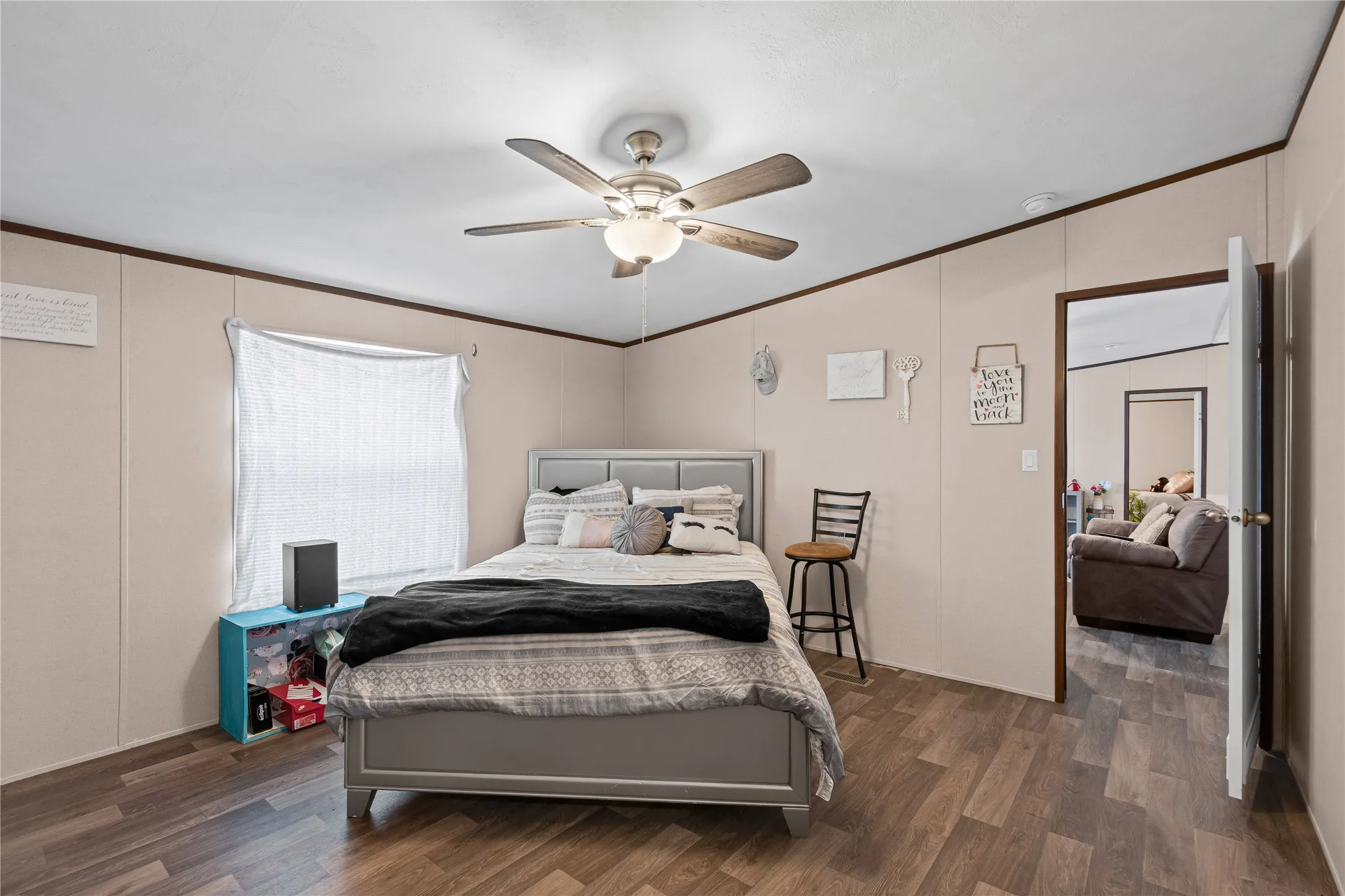 Bedroom featuring wood finished floors, a ceiling fan, crown molding, and a decorative wall
