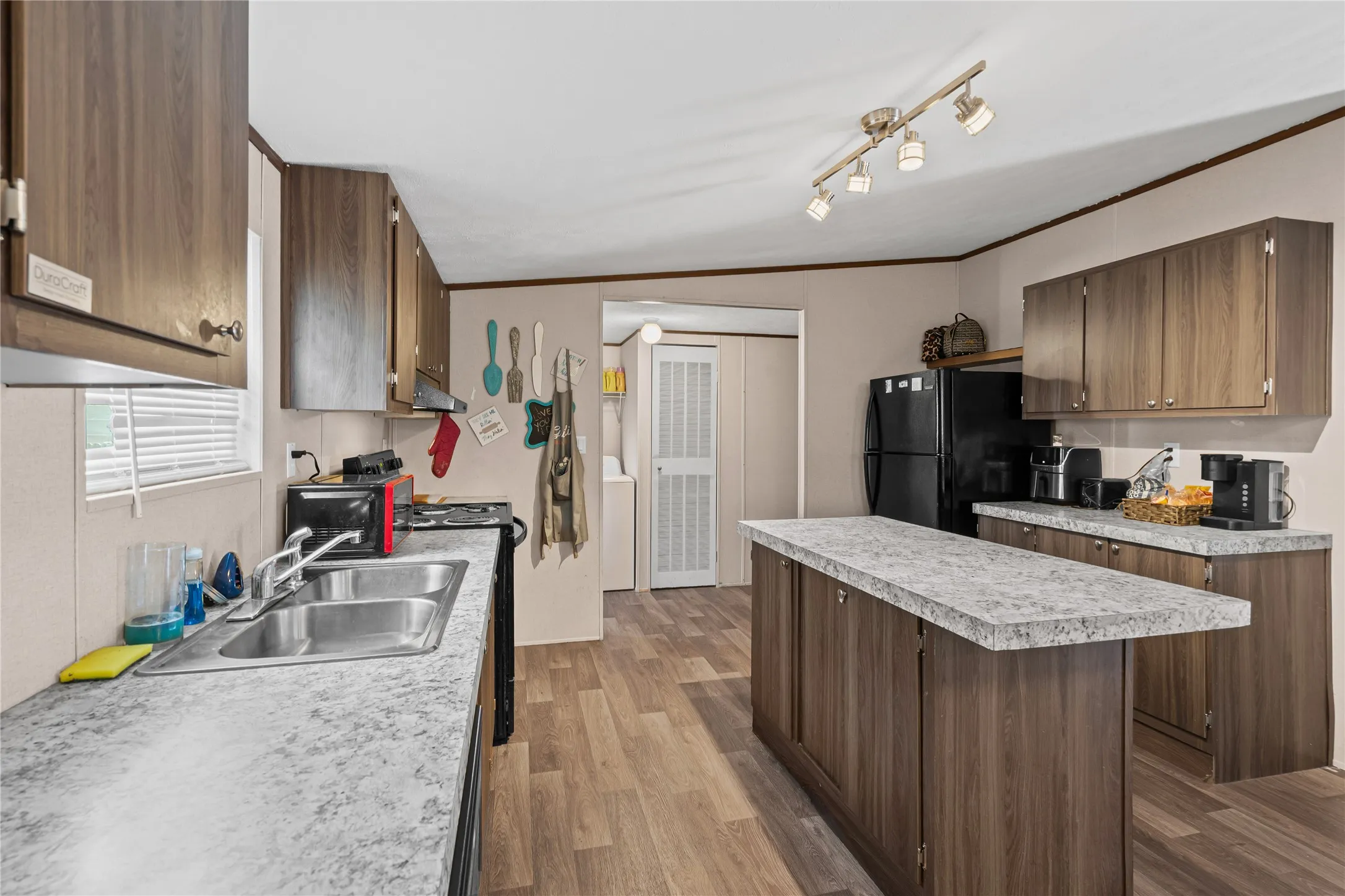 Kitchen featuring freestanding refrigerator, a sink, light countertops, electric range, and under cabinet range hood